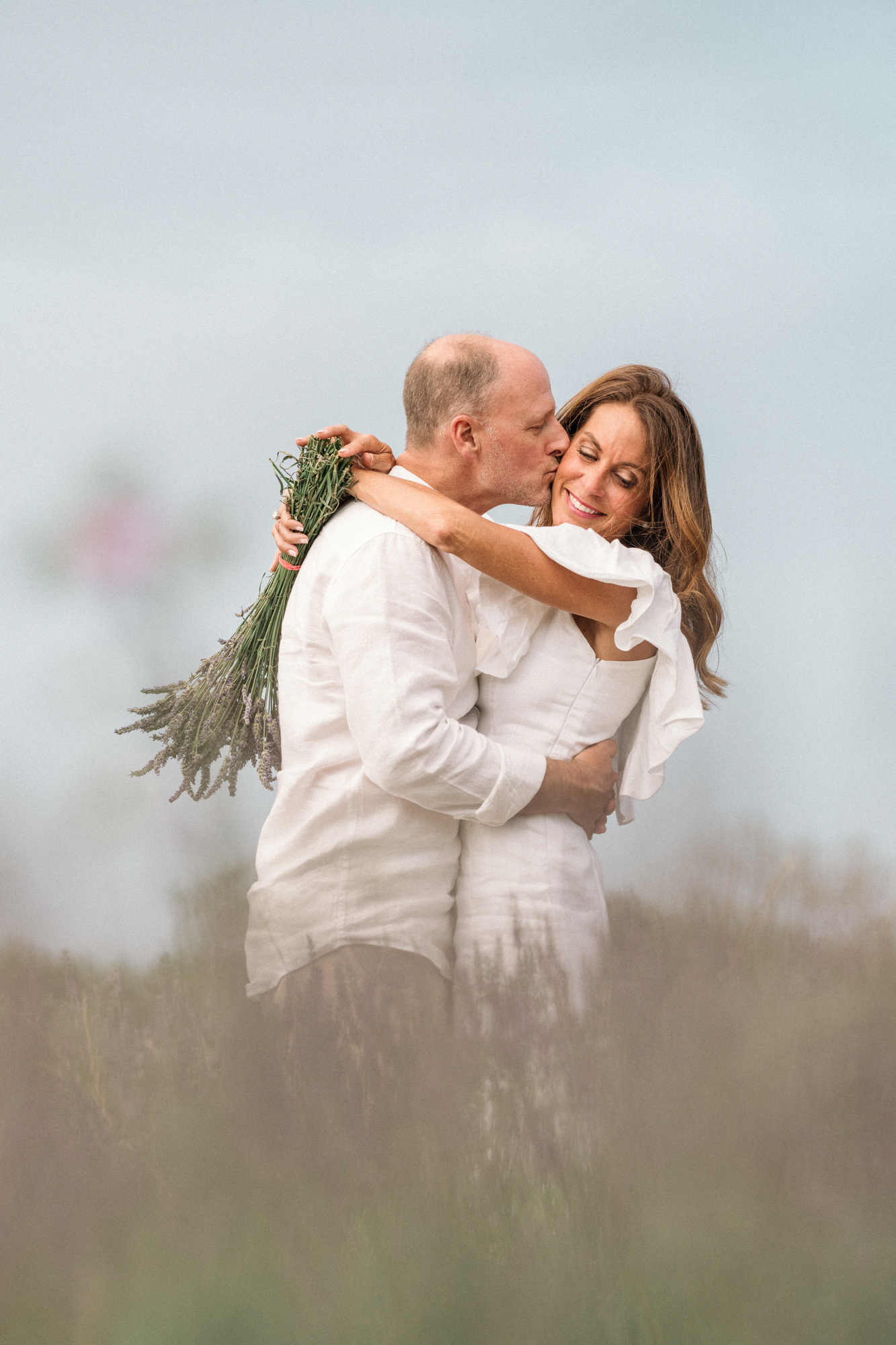 man kisses woman on cheek in lavender fields of Provence