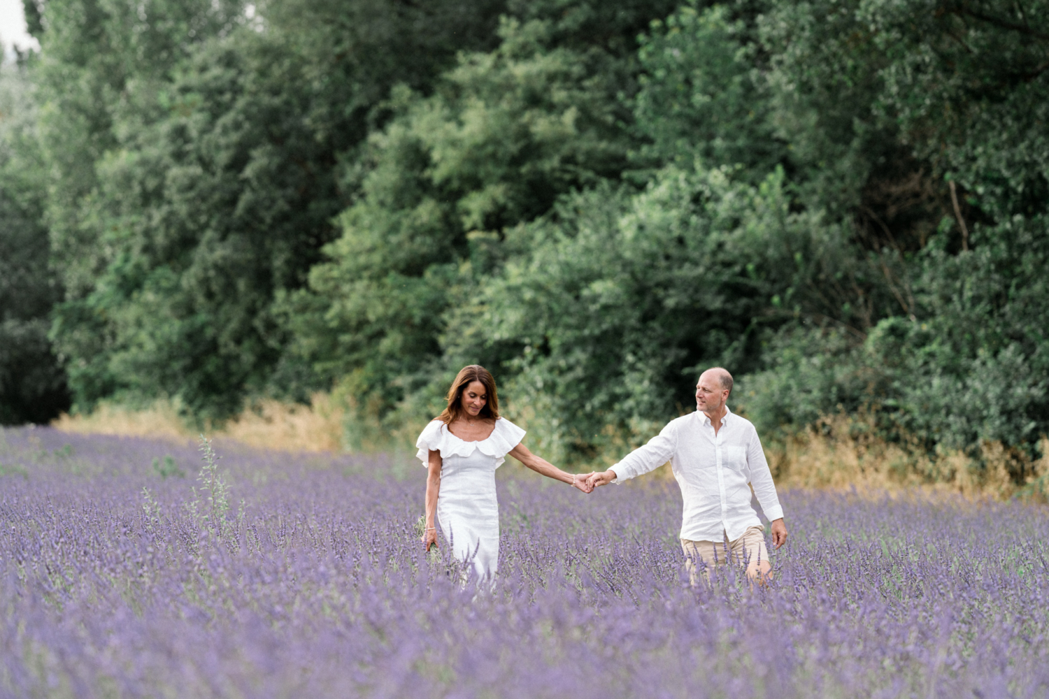 woman and man holding hands in lavender field