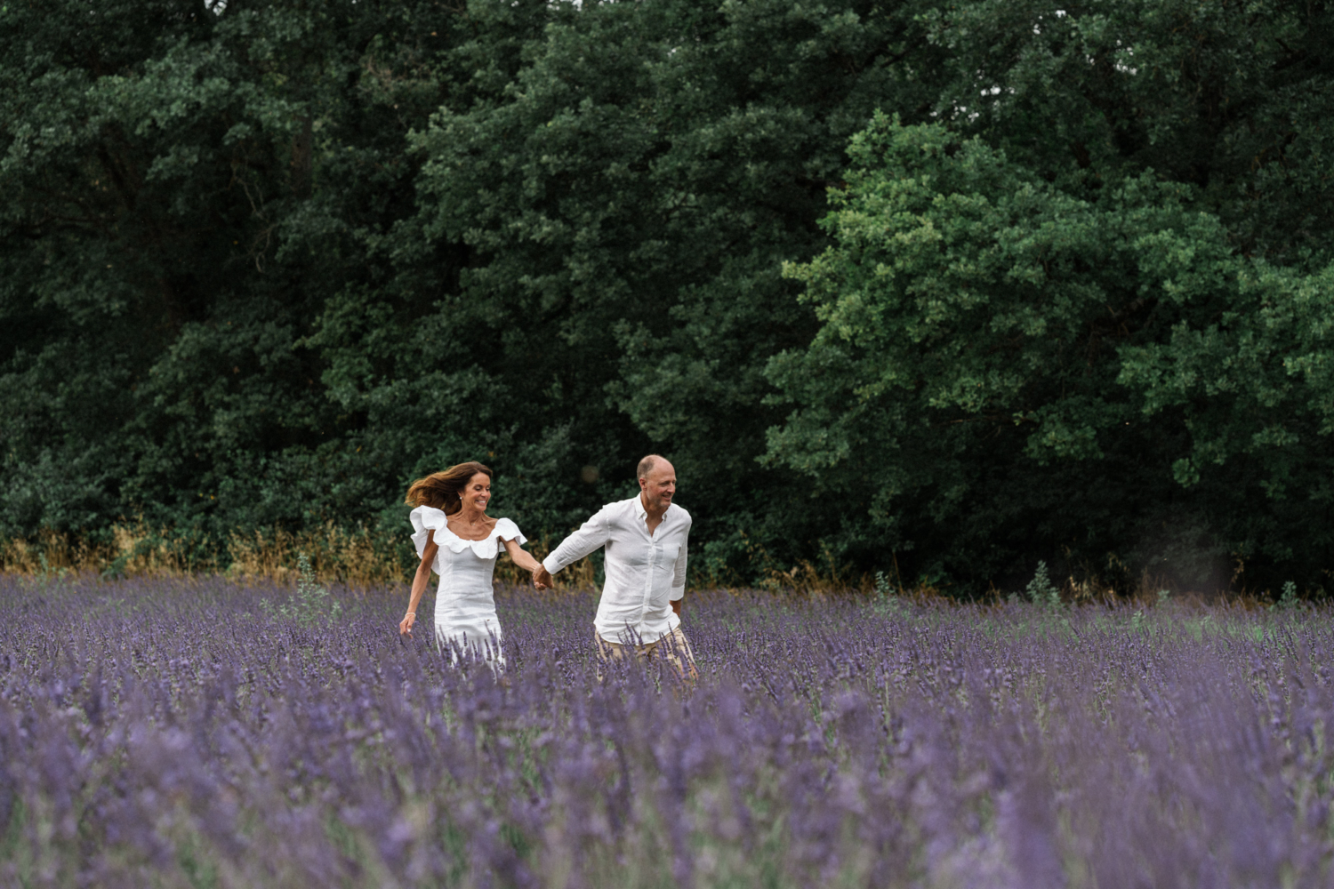 couple run hand and hand laughing in lavender field