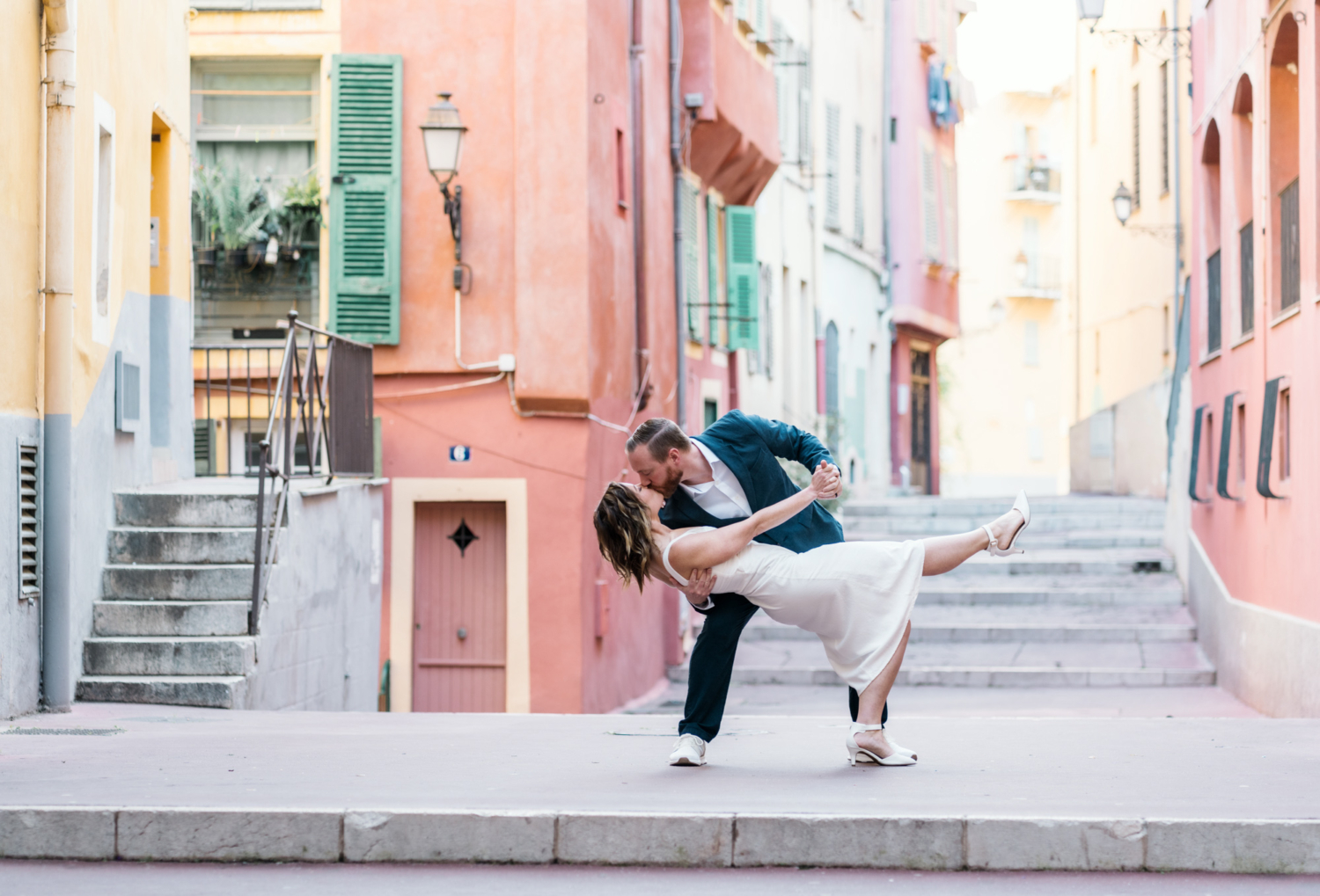 man dips woman backward and kisses her in colorful neighborhood