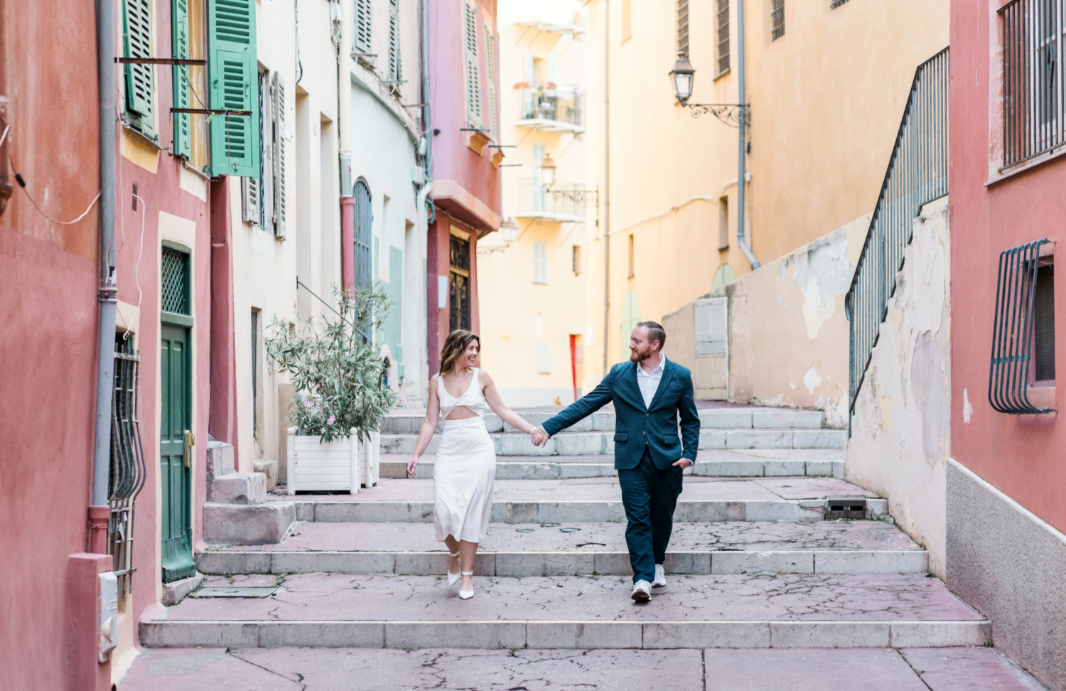 married couple laugh and walk on a stroll in old town nice france