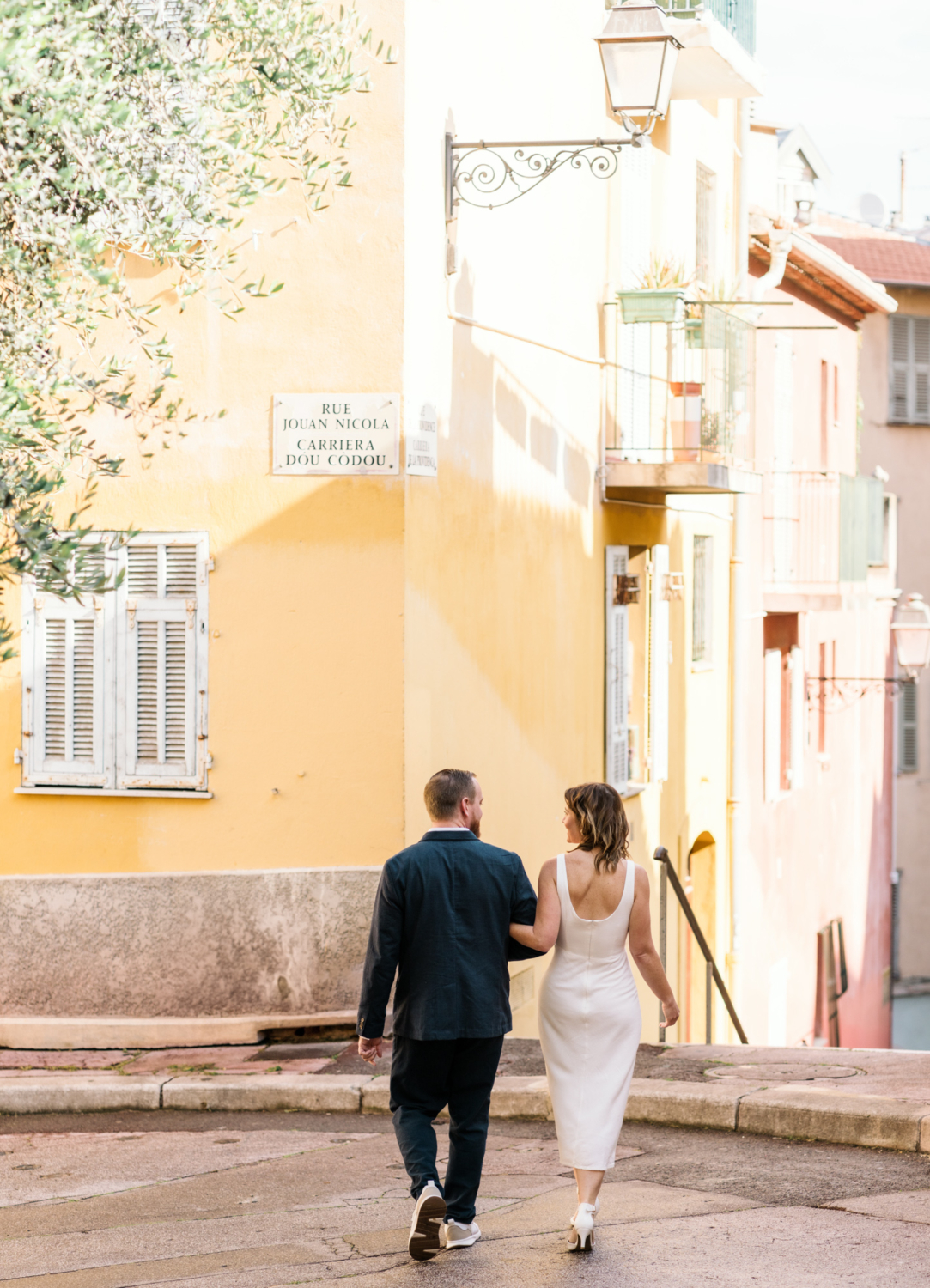 man and woman walk toward yellow building in colorful old nice france