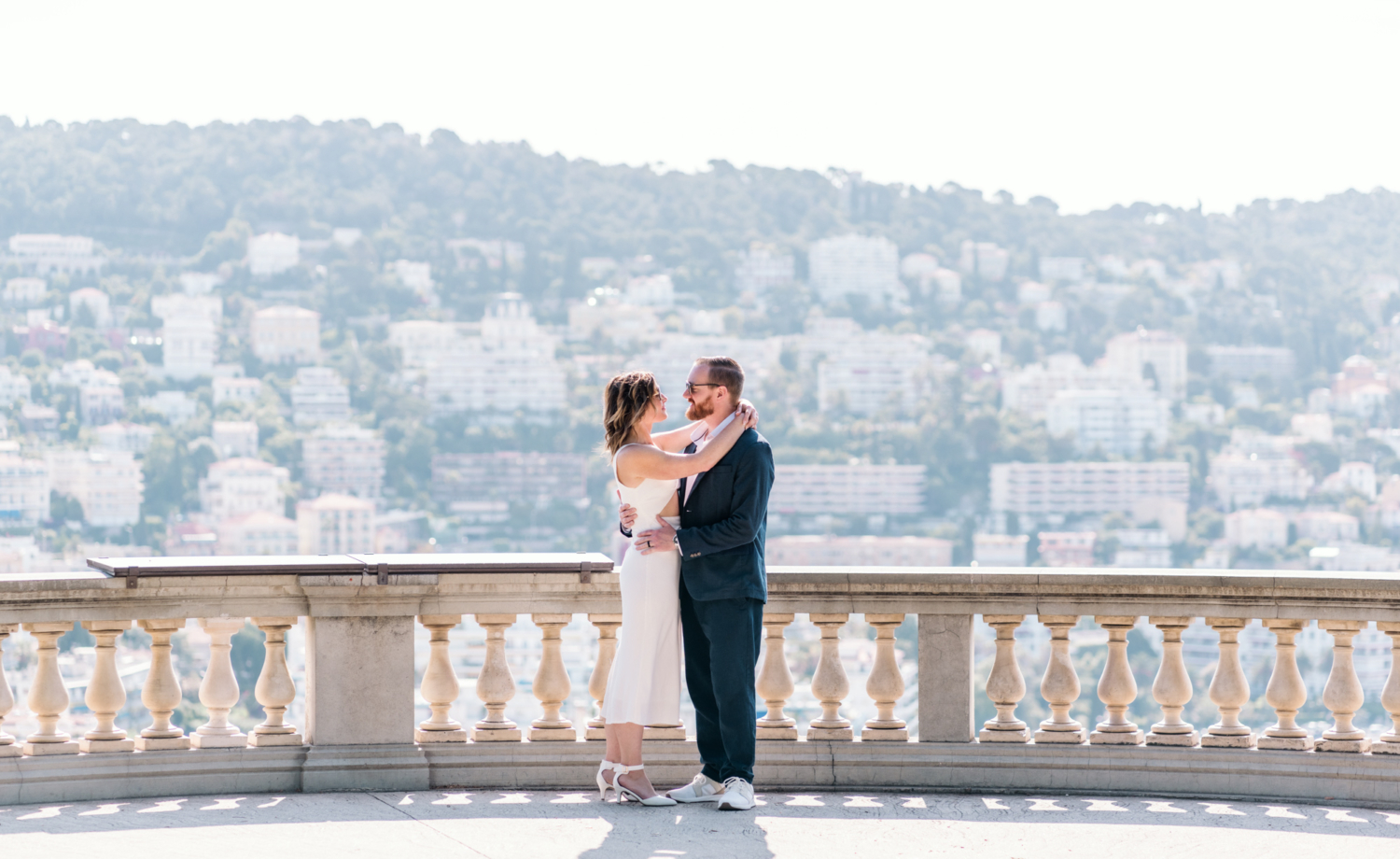 couple wearing sunglasses embrace with amazing view in old town nice