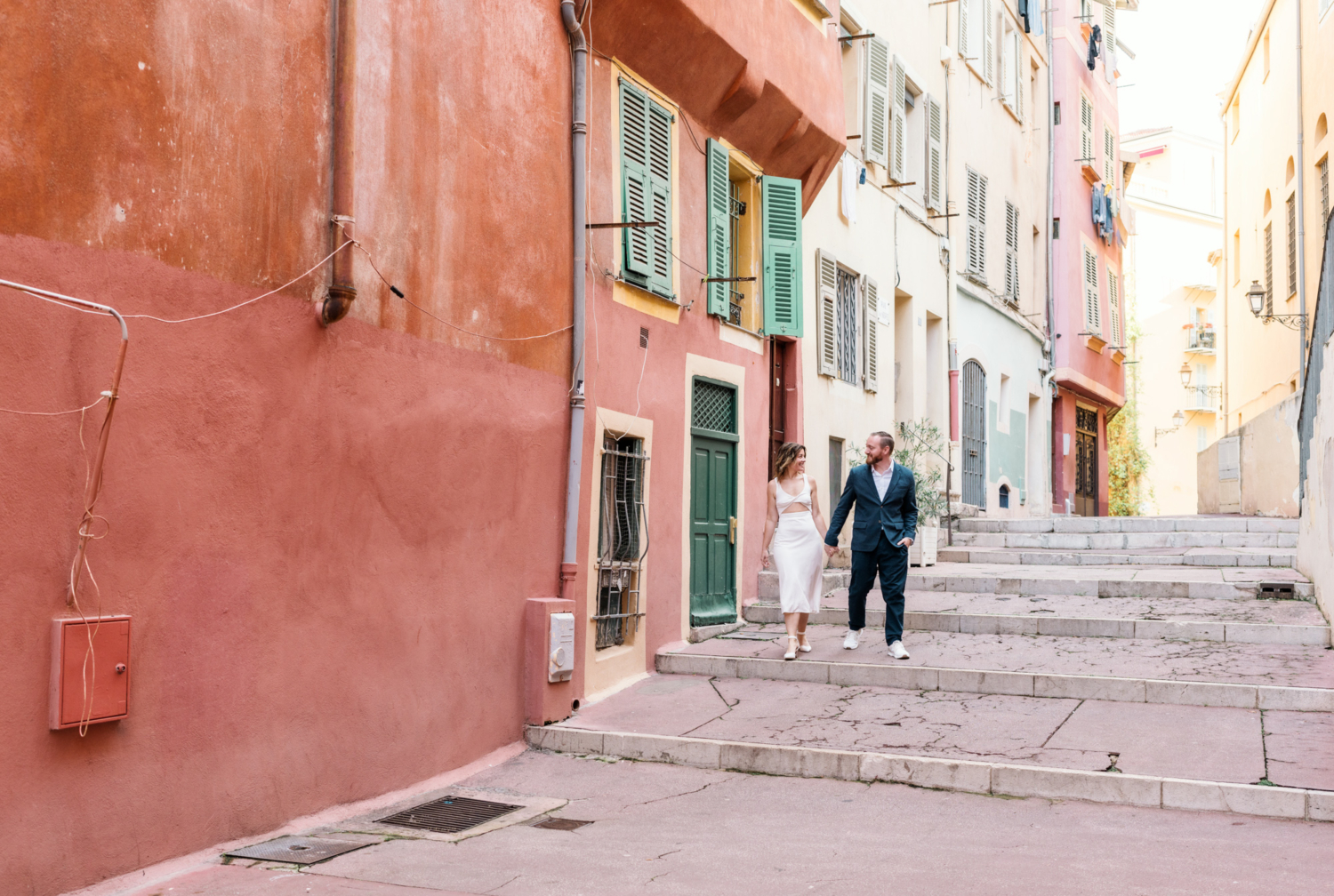 man and woman walk hand in hand through colorful neighborhood in nice france