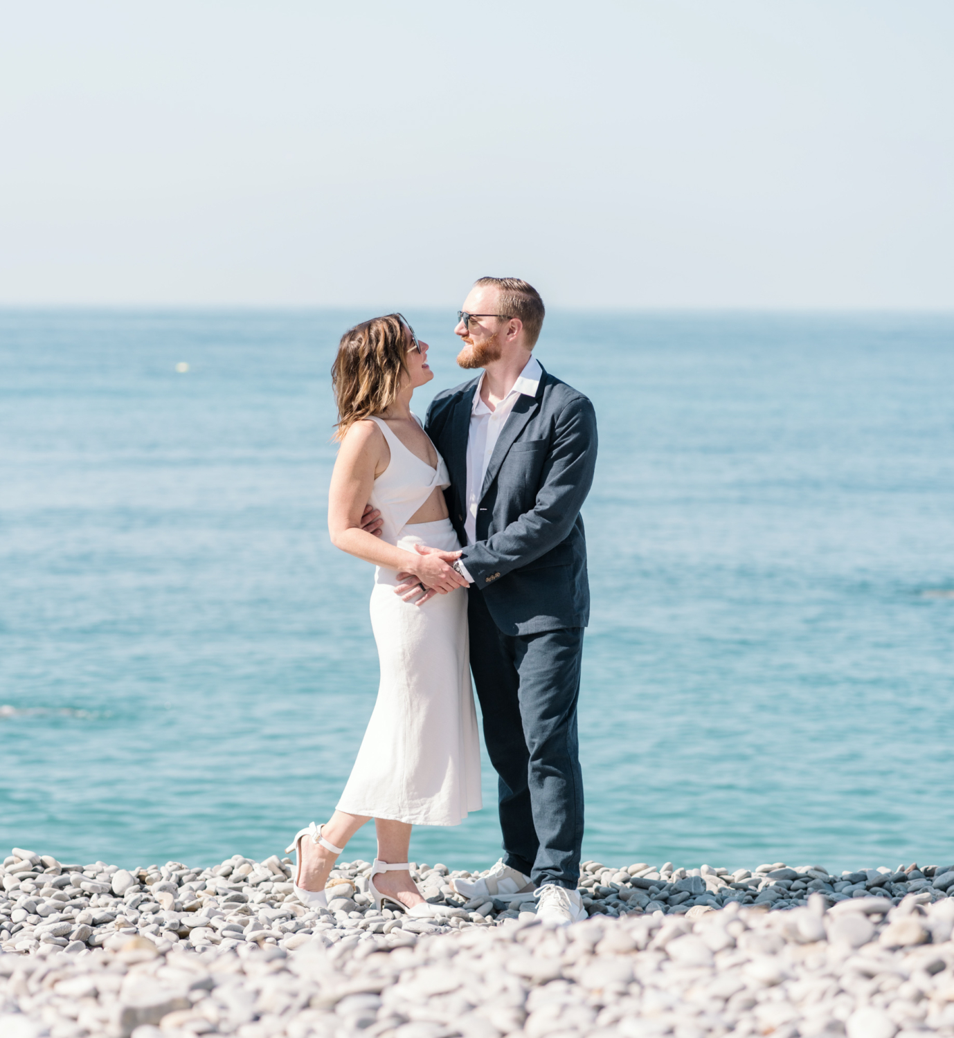 man and woman smile at beach with blue water in nice france