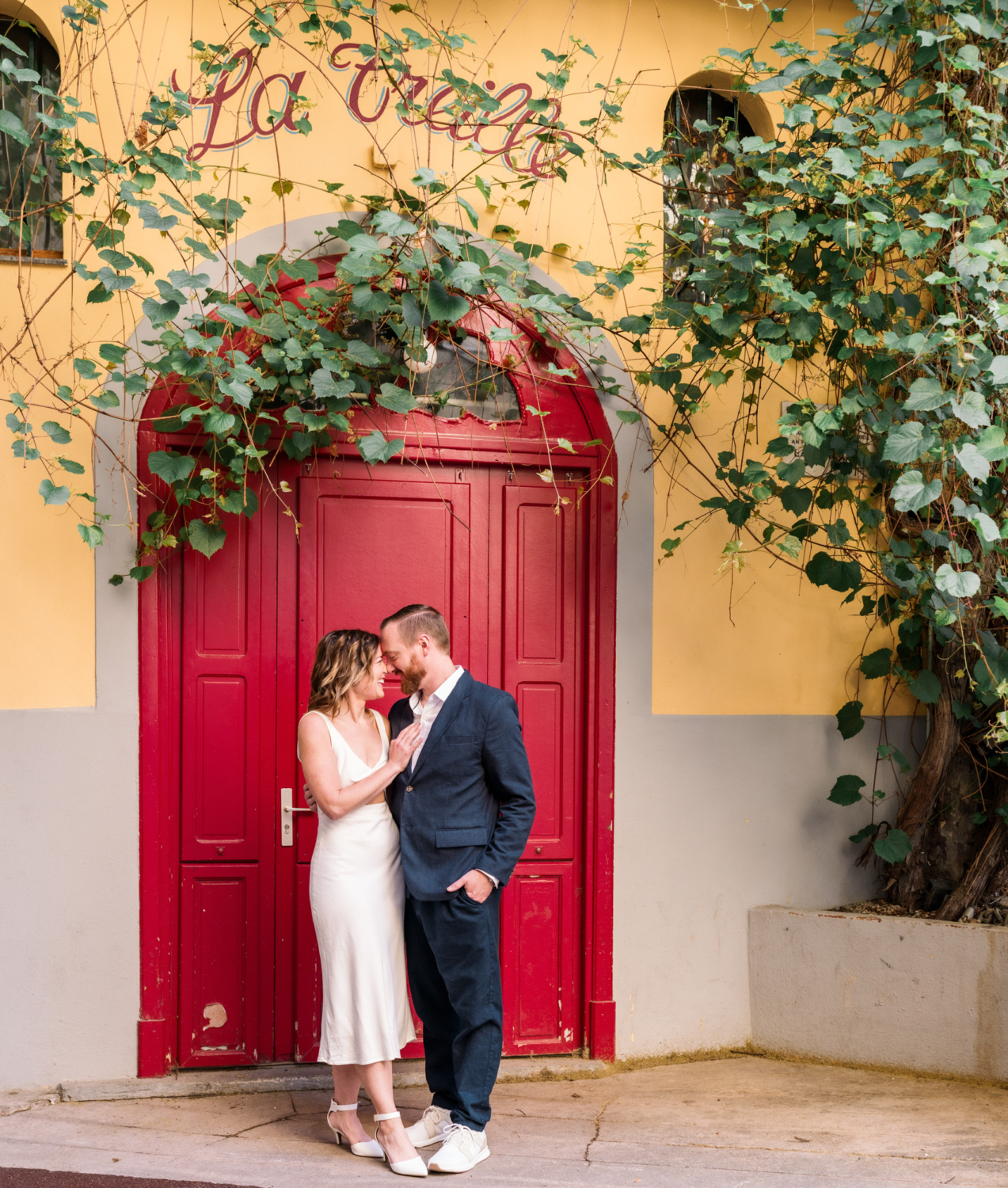 man and woman laugh in front of red door in nice france