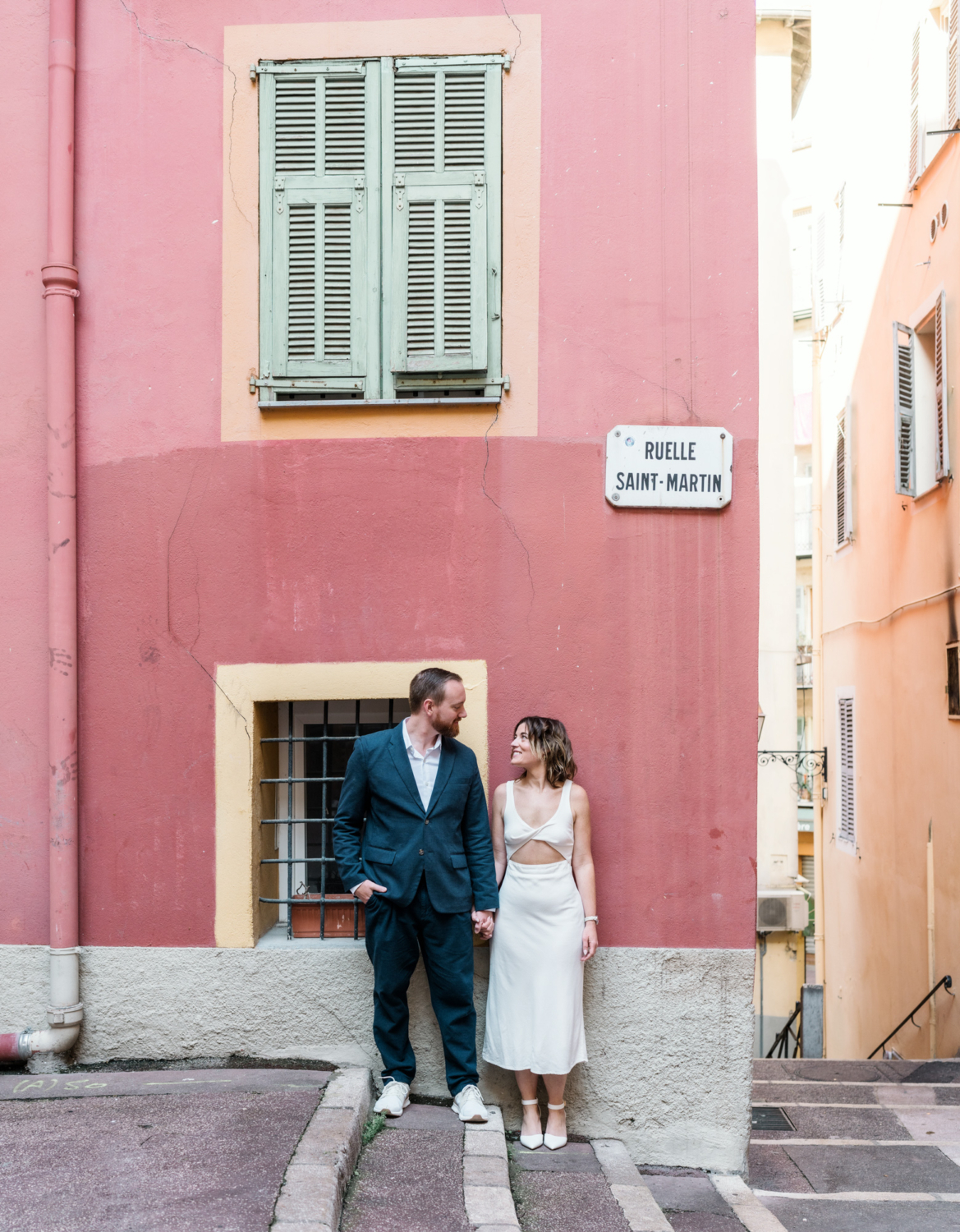 man and woman stand side by side next to colorful building