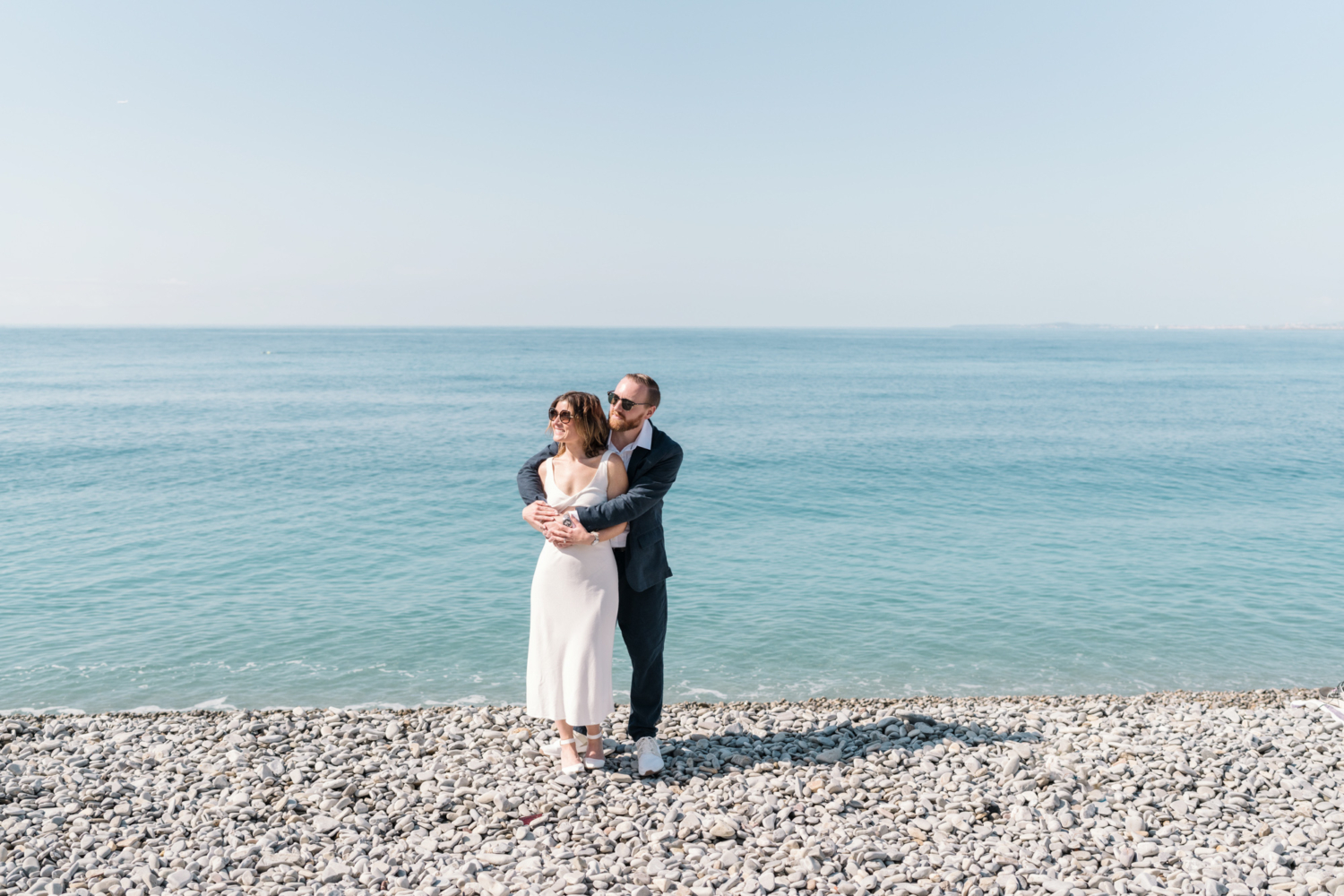 married couple embrace on beach with sea background in nice france