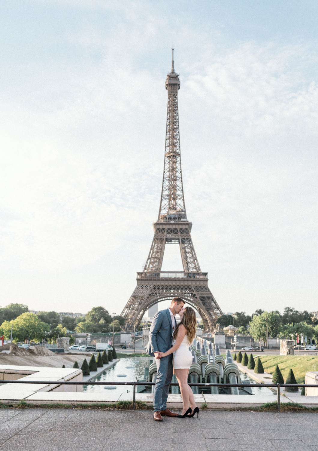 engaged couple kiss with distant view of eiffel tower in paris