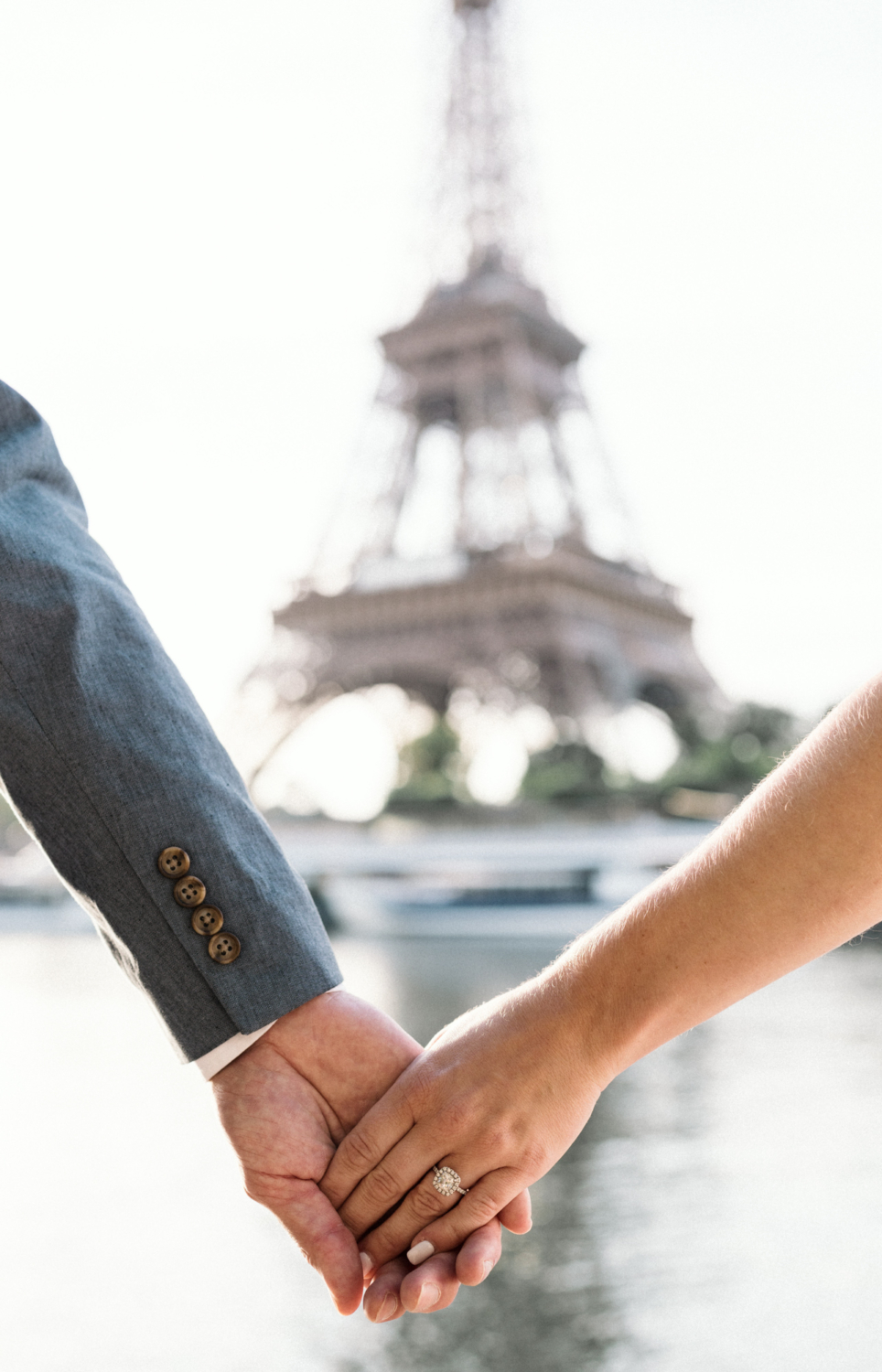 engaged couple holds hands with engagement ring at eiffel tower