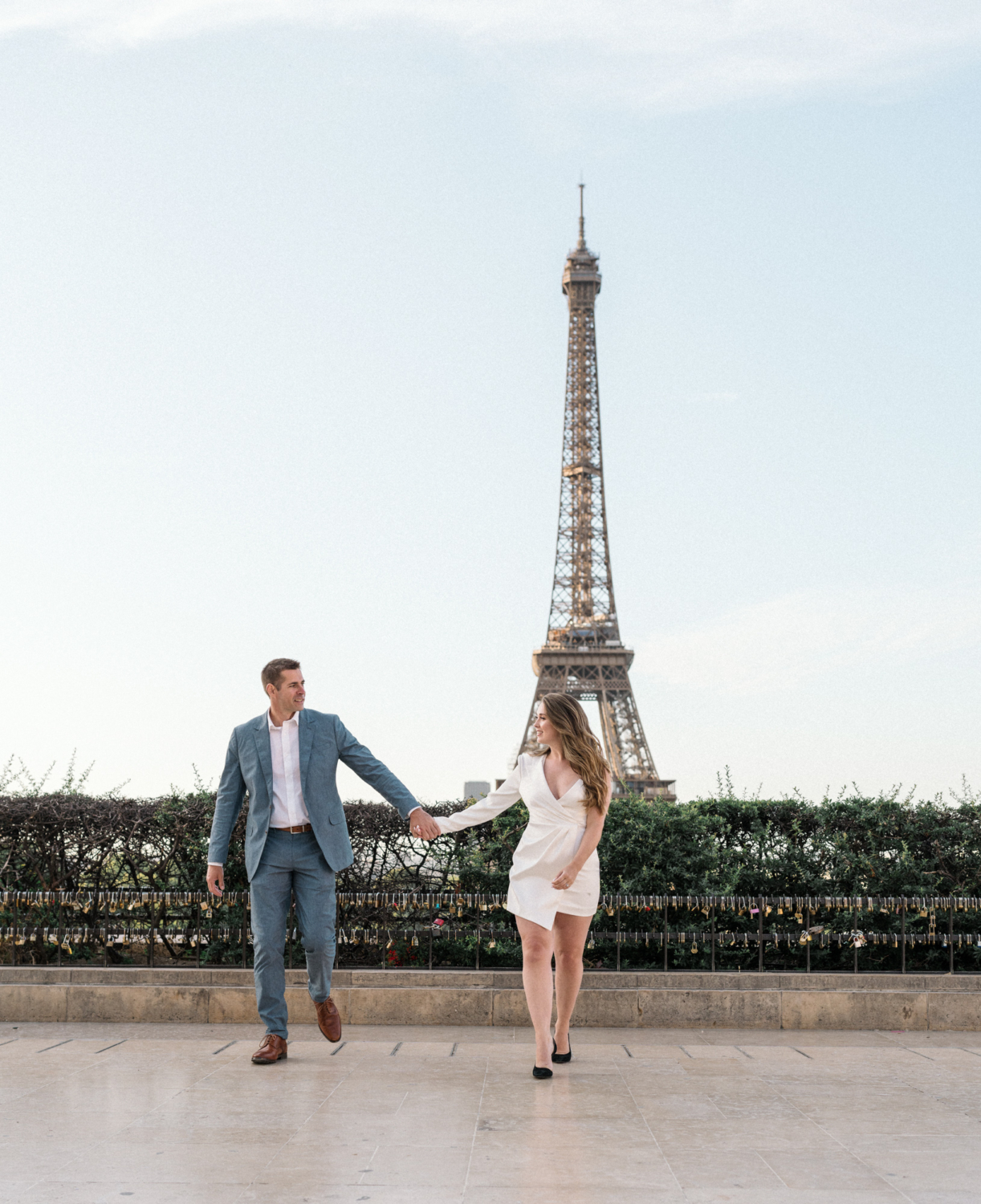 engaged couple walk hand in hand at trocadero with eiffel tower in background