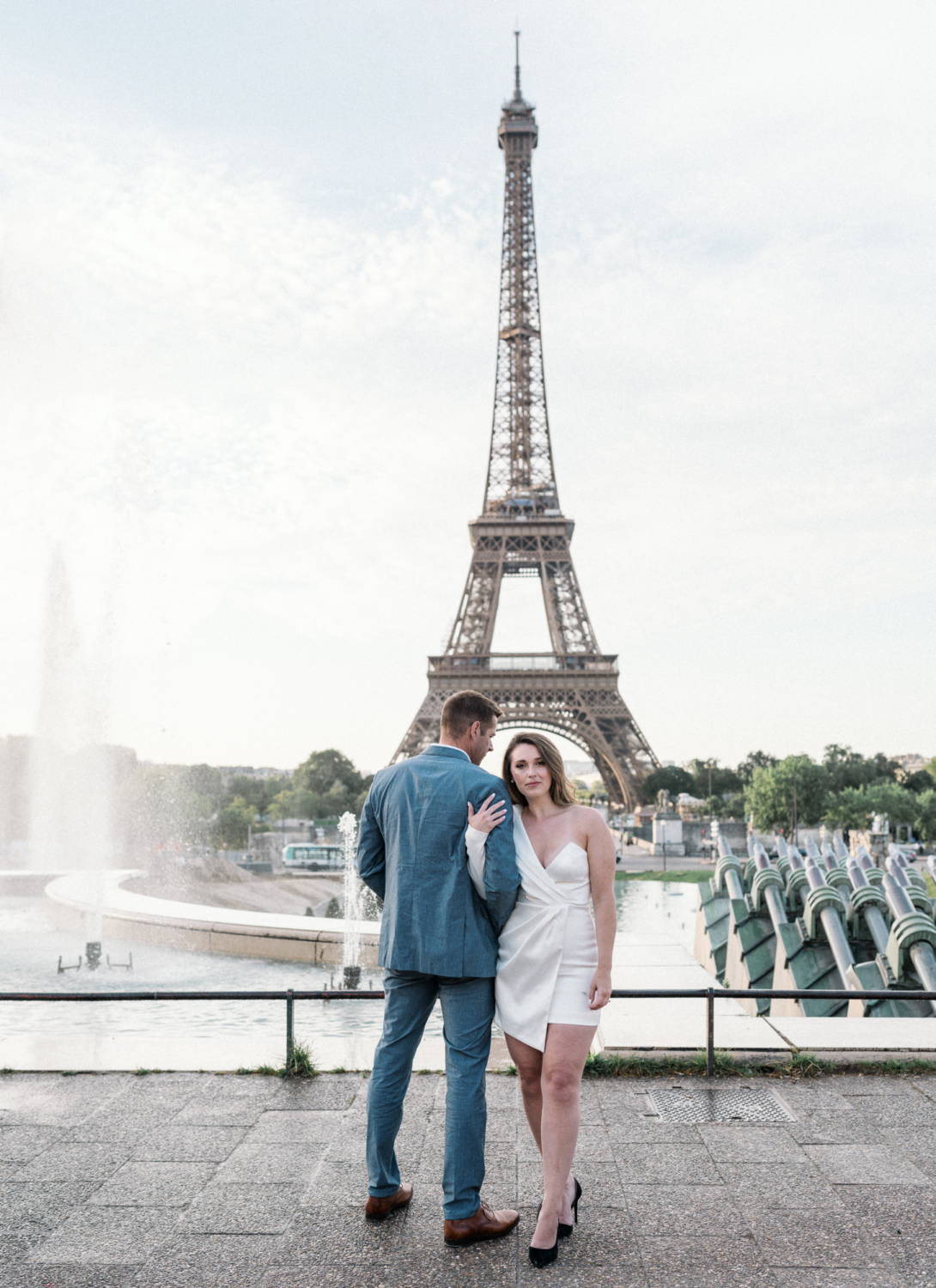 engaged couple embrace with a view of the eiffel tower in paris