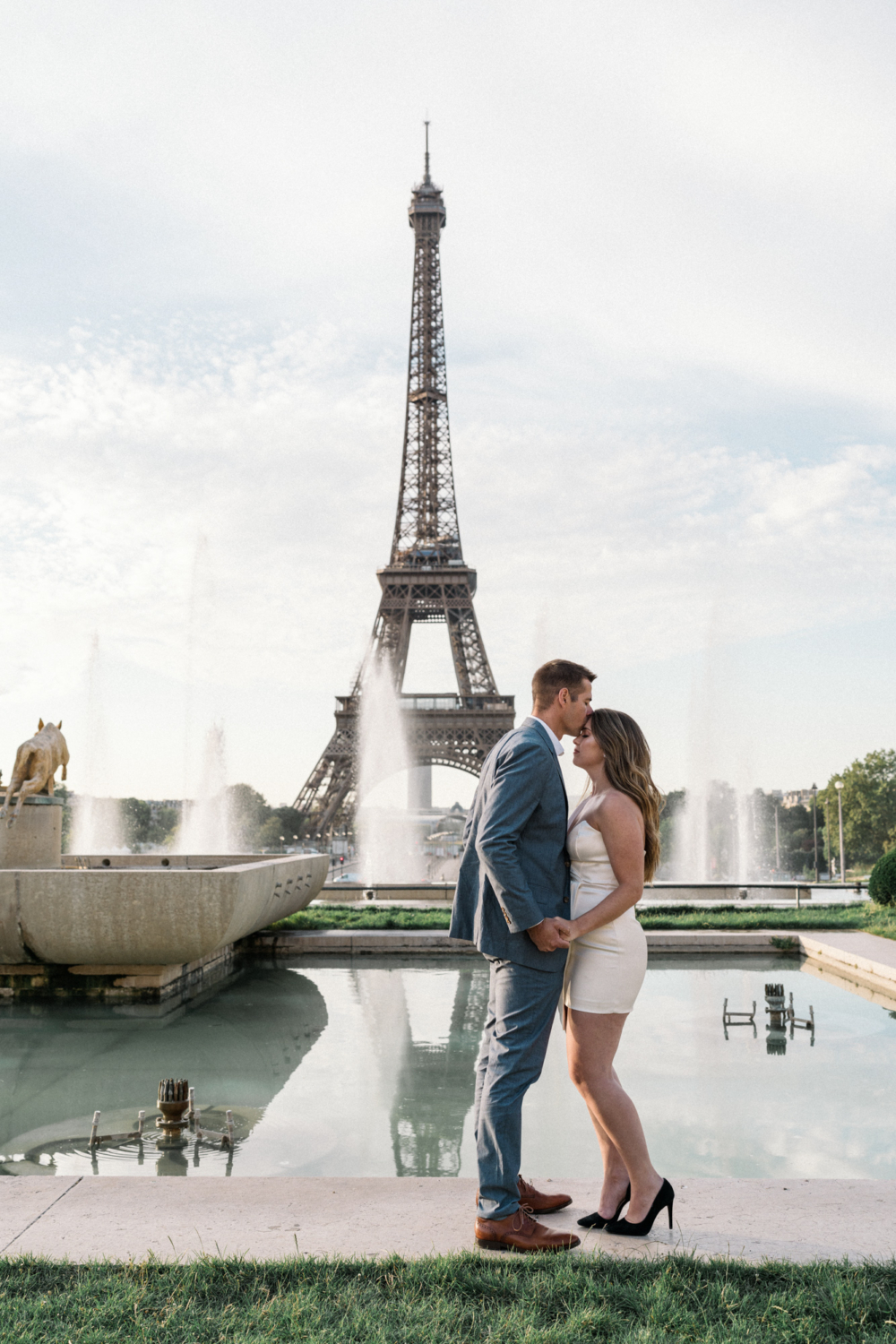 man kisses woman's forehead with a view of the eiffel tower in paris