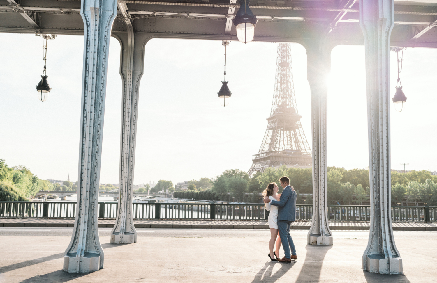 engaged couple smile and dance under bridge in paris