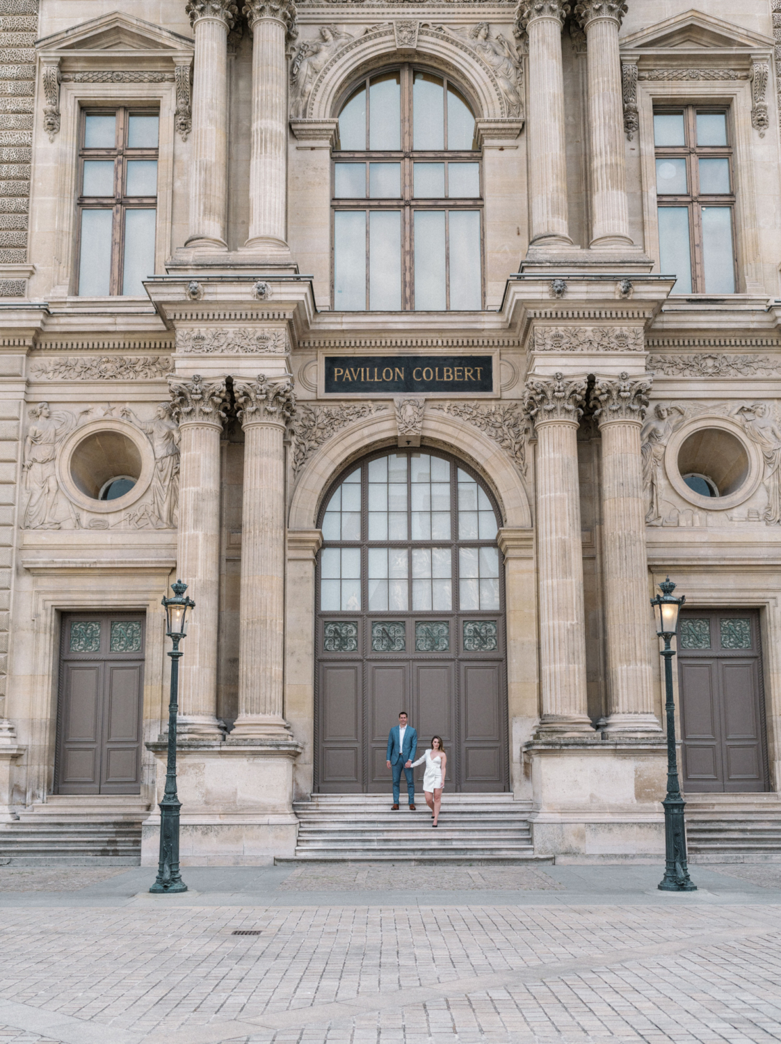 engaged couple walk down staricase at louvre in paris