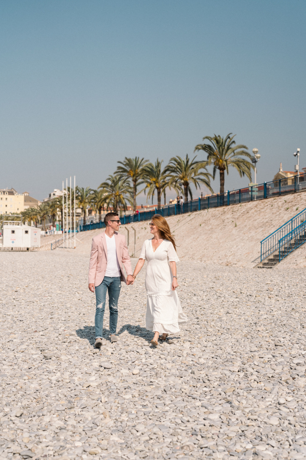 couple wearing sunglasses walking on beach in nice france