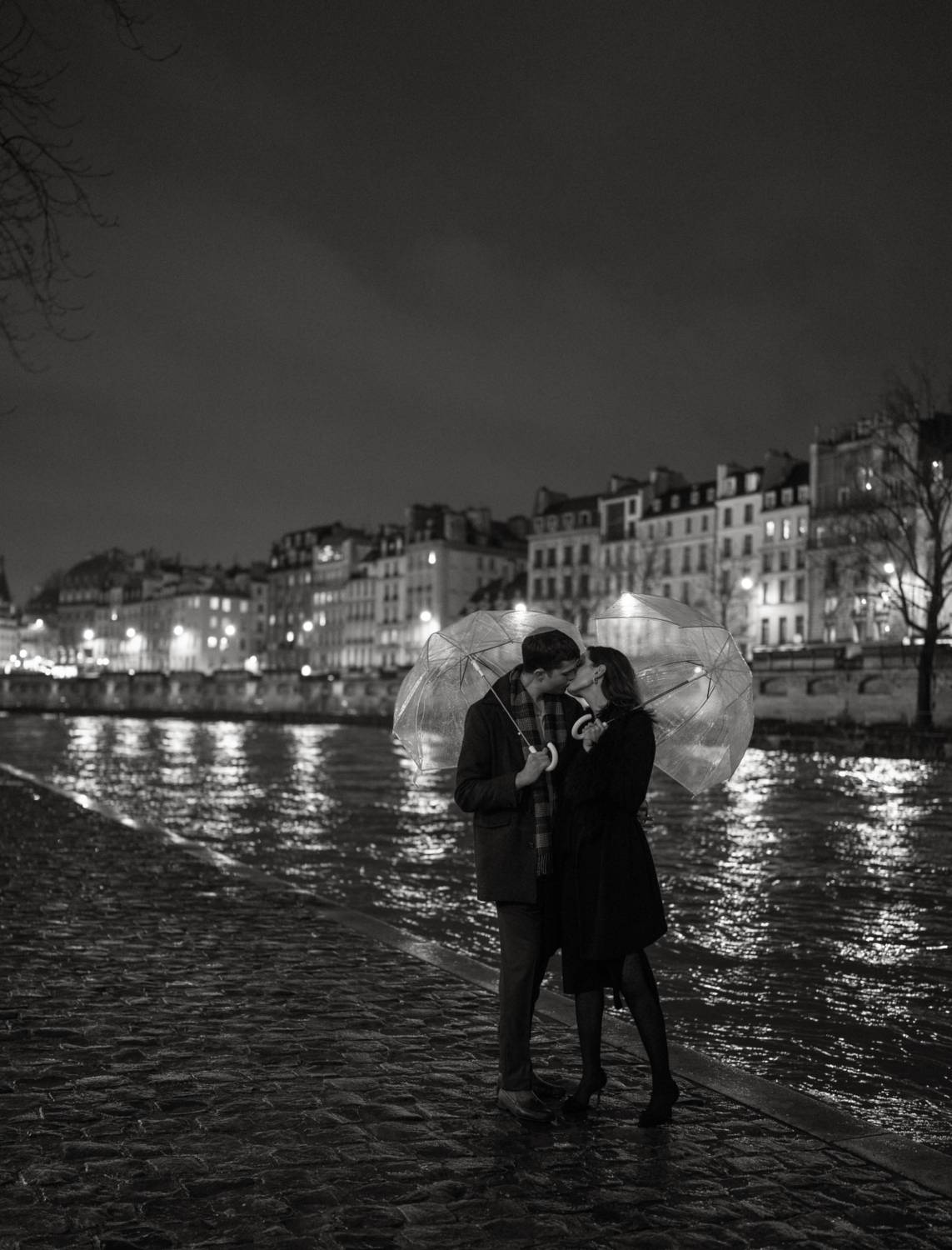 engaged couple with umbrellas kiss in paris rain