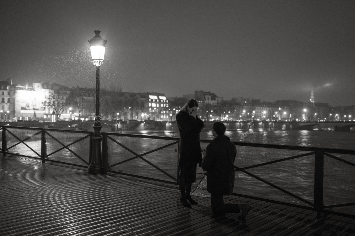 man on one knee proposes to woman in rain in paris