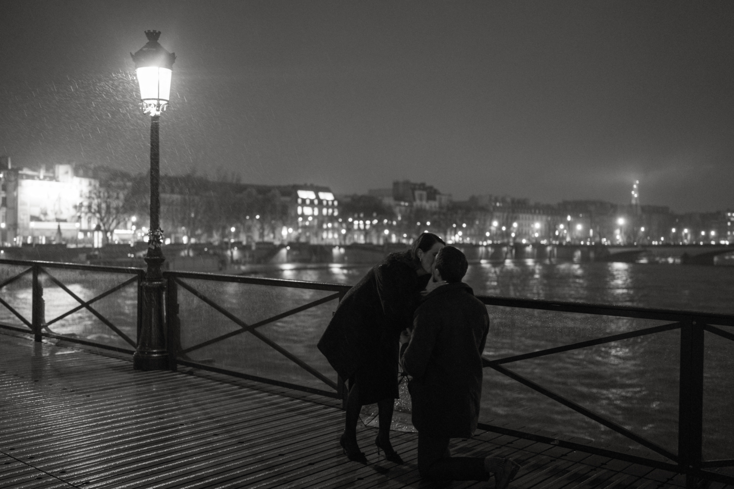 woman kisses man after he proposes in the rain in paris