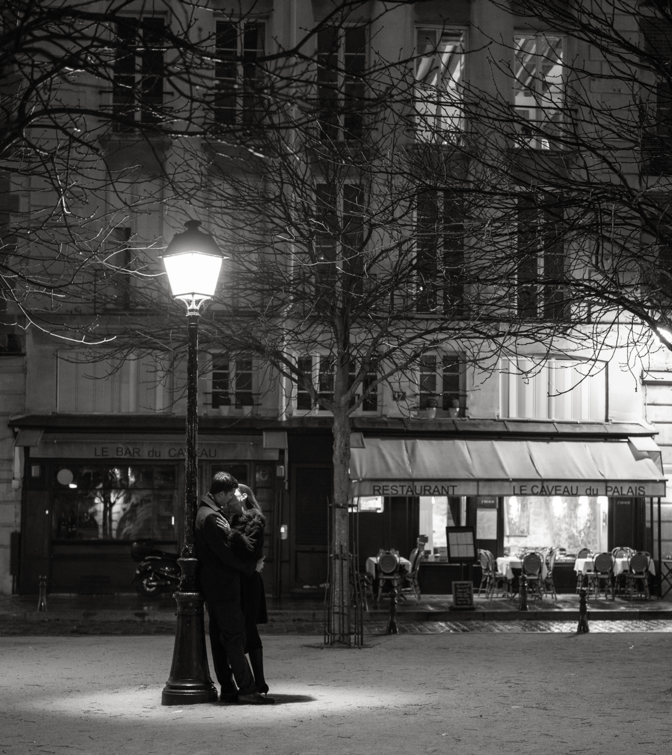 engaged couple kiss at place dauphine at night in paris