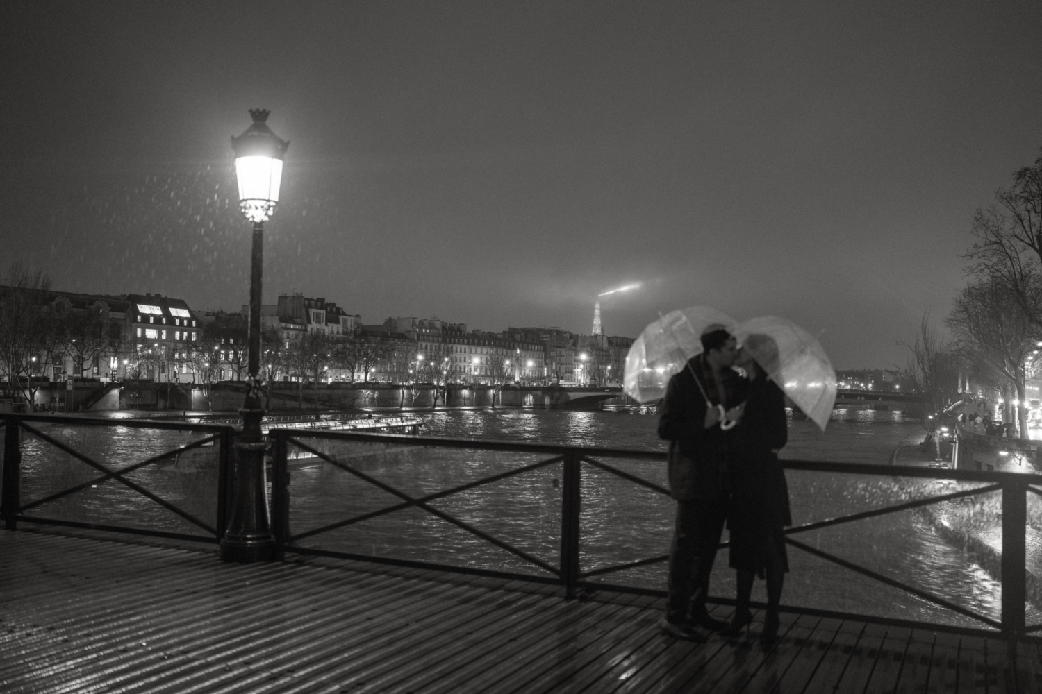 engaged couple with umbrella kiss in the rain in paris