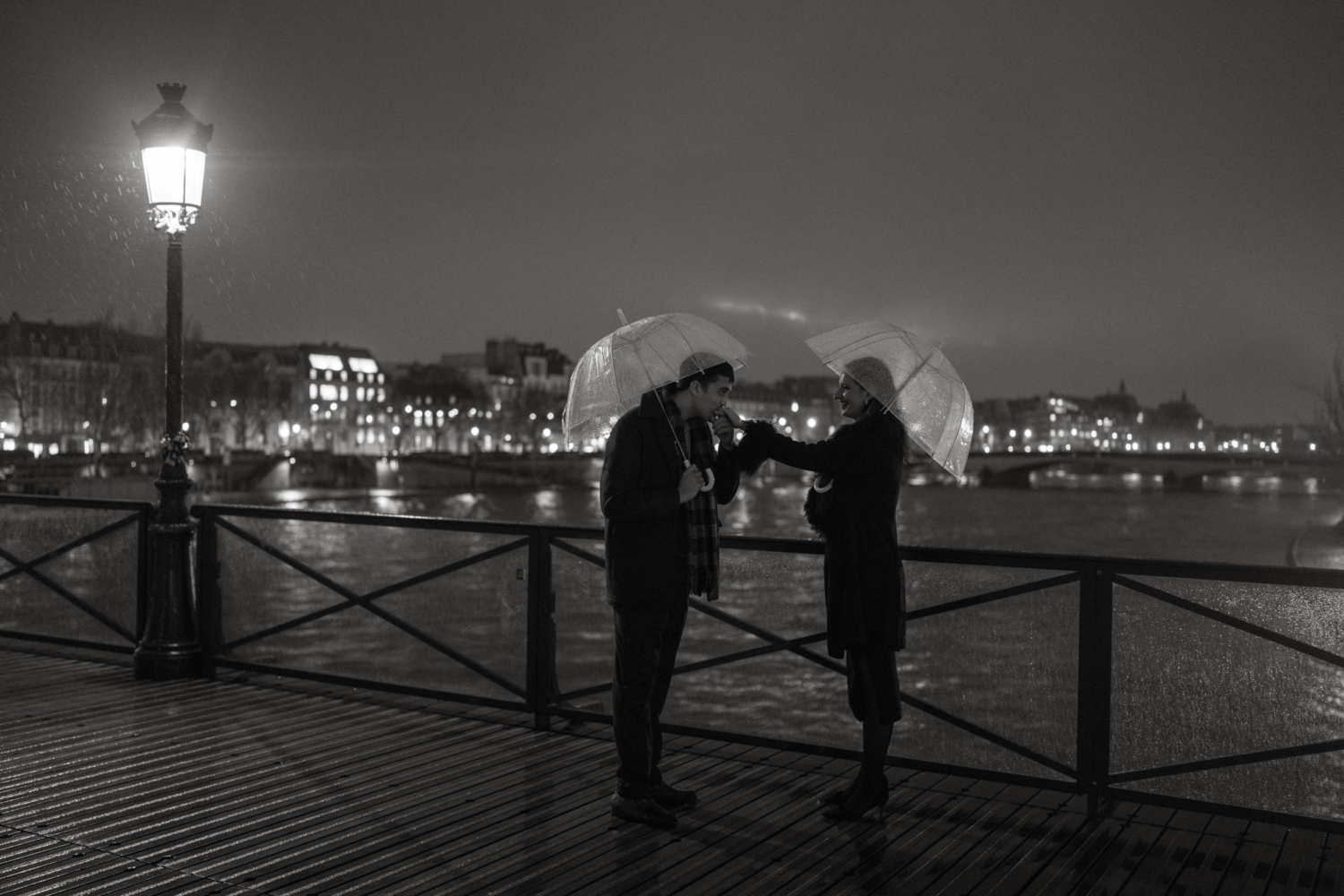 man kisses woman's hand in the rain in paris