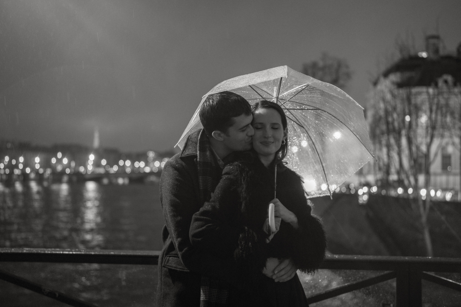 engaged couple with umbrella embrace in the rain in paris