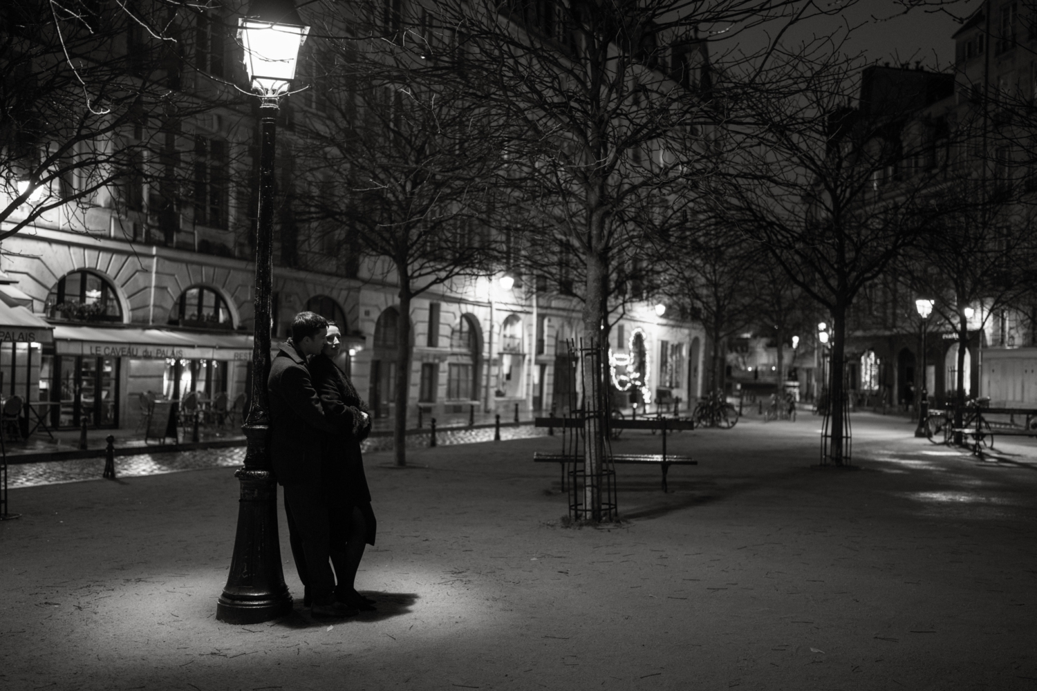 engaged couple lean on each other at place dauphine at night in paris