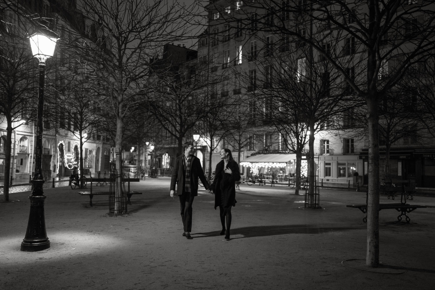 engaged couple walk at place dauphine at night in paris