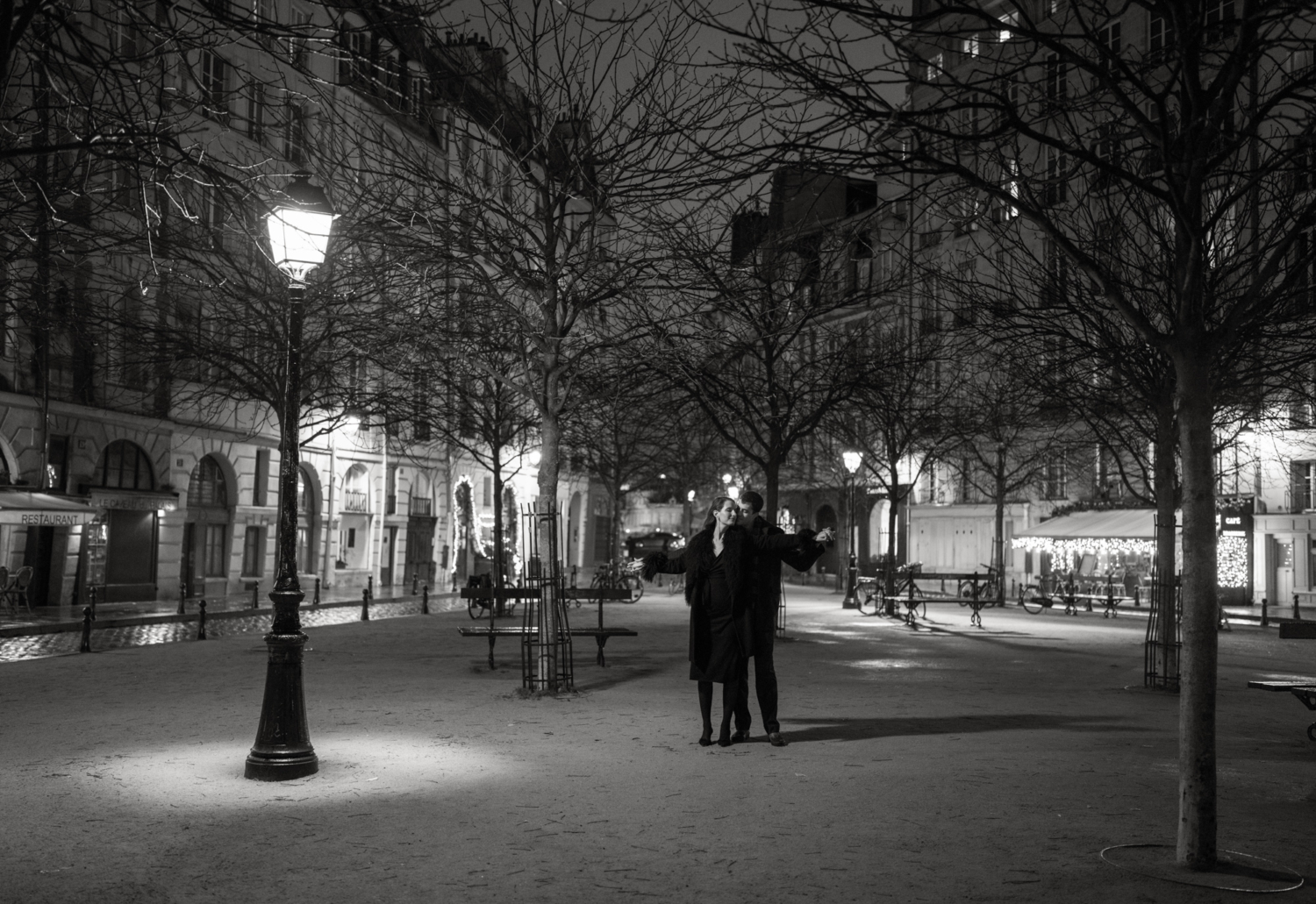 engaged couple embrace at place dauphine at night in paris