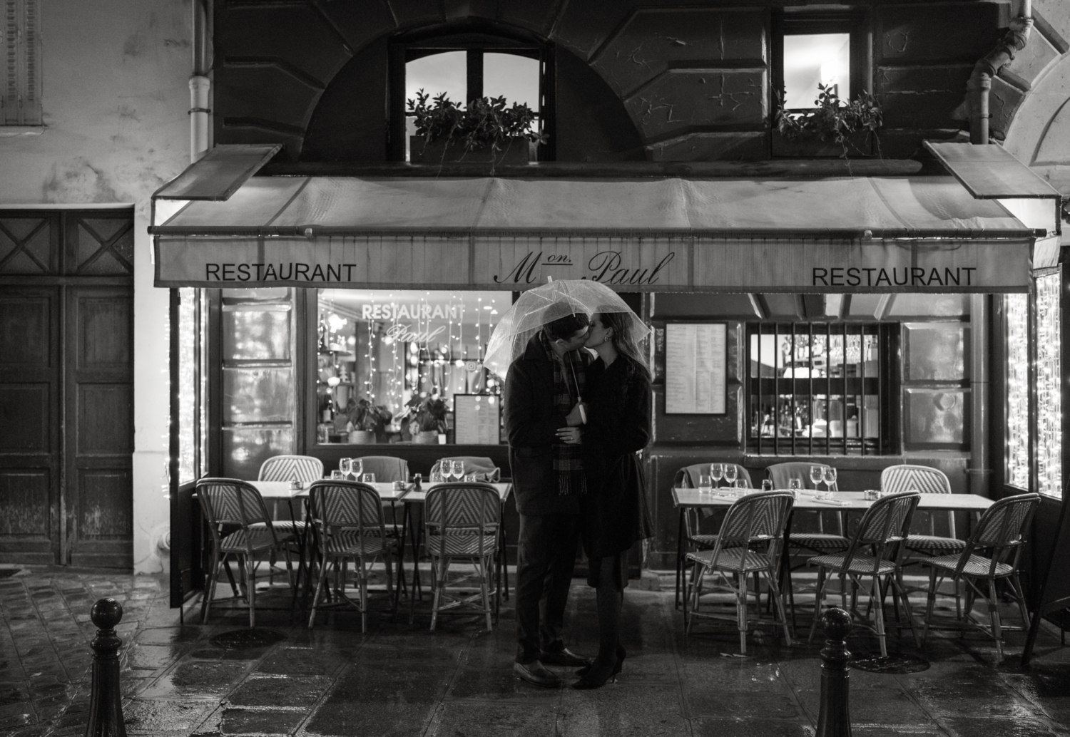 engaged couple with umbrellas kiss passionately at place dauphine paris