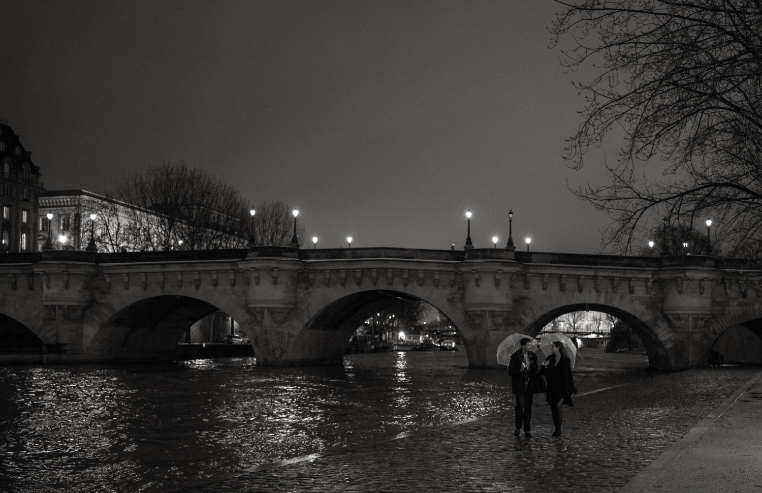 engaged couple with umbrellas walk in the rain in paris