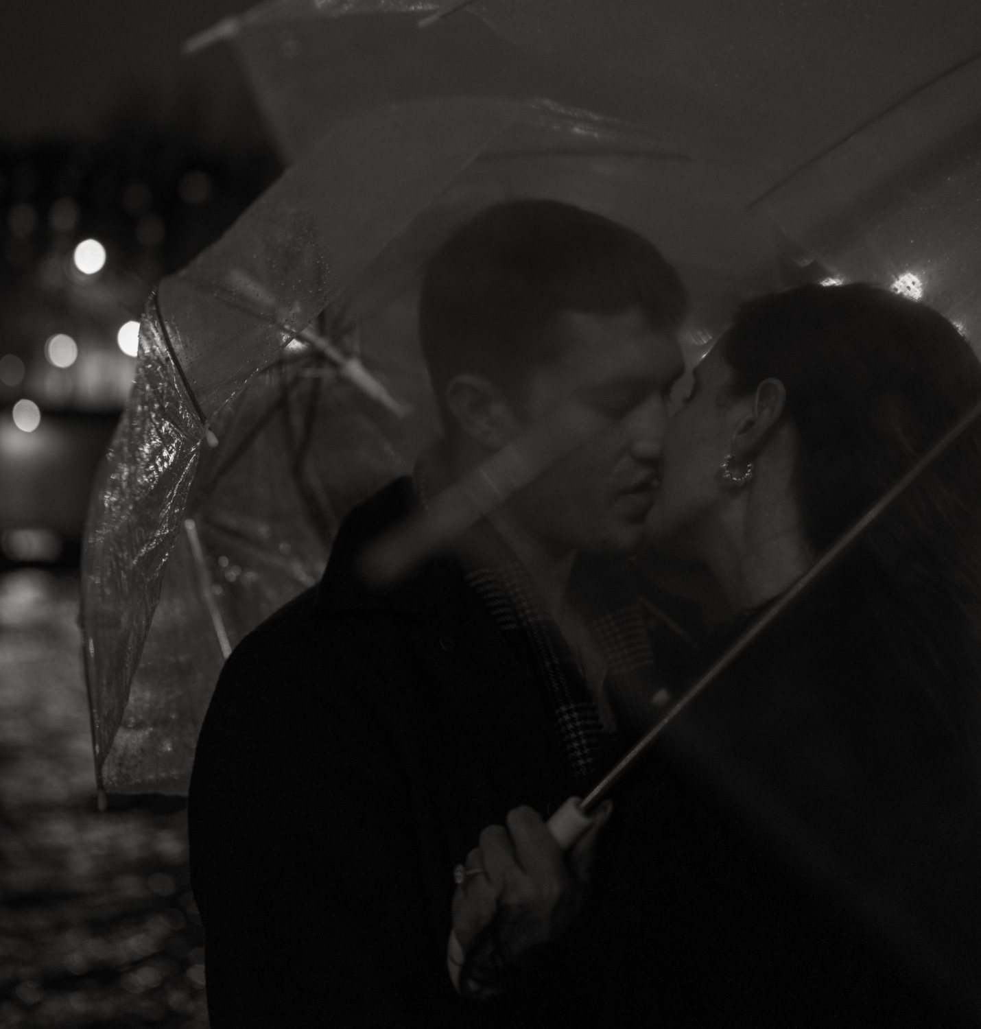 engaged couple with umbrellas kiss passionately in paris