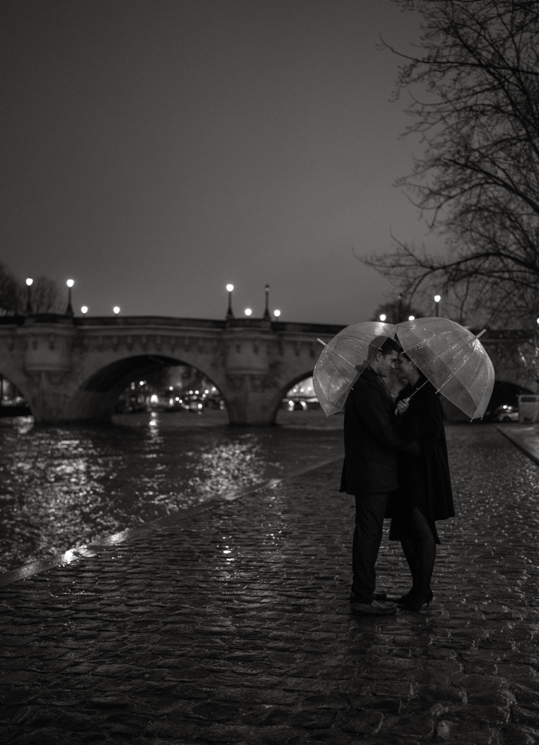 engaged couple with umbrellas at pont neuf in paris