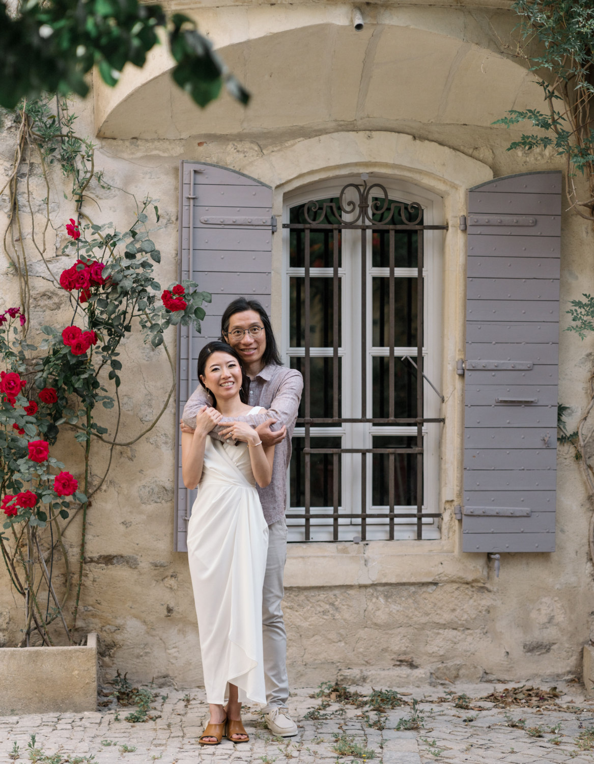 beautiful chinese couple embrace in front of rose bush in arles france