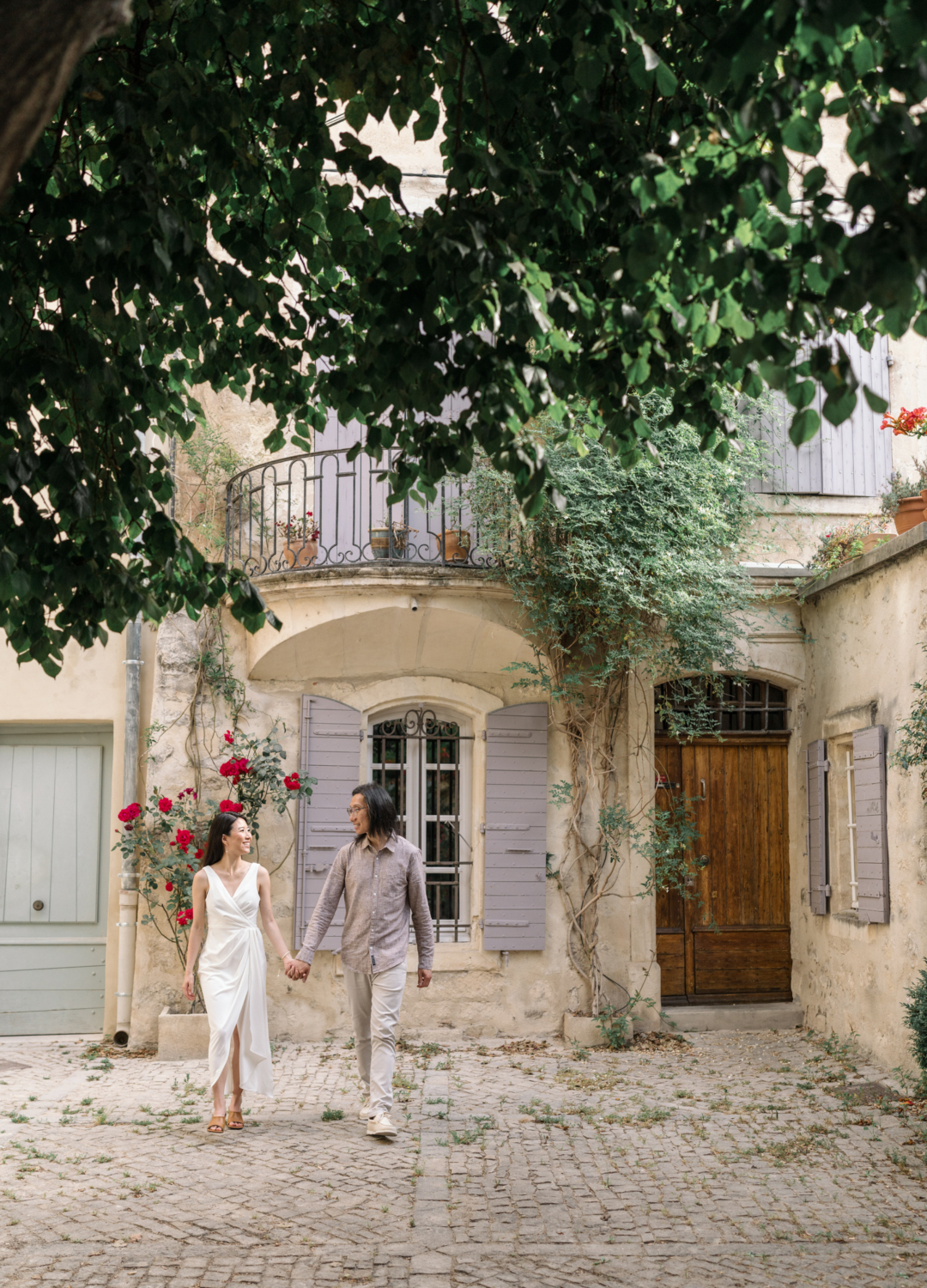 man and woman walk hand in hand in cute neighborhood in arles france