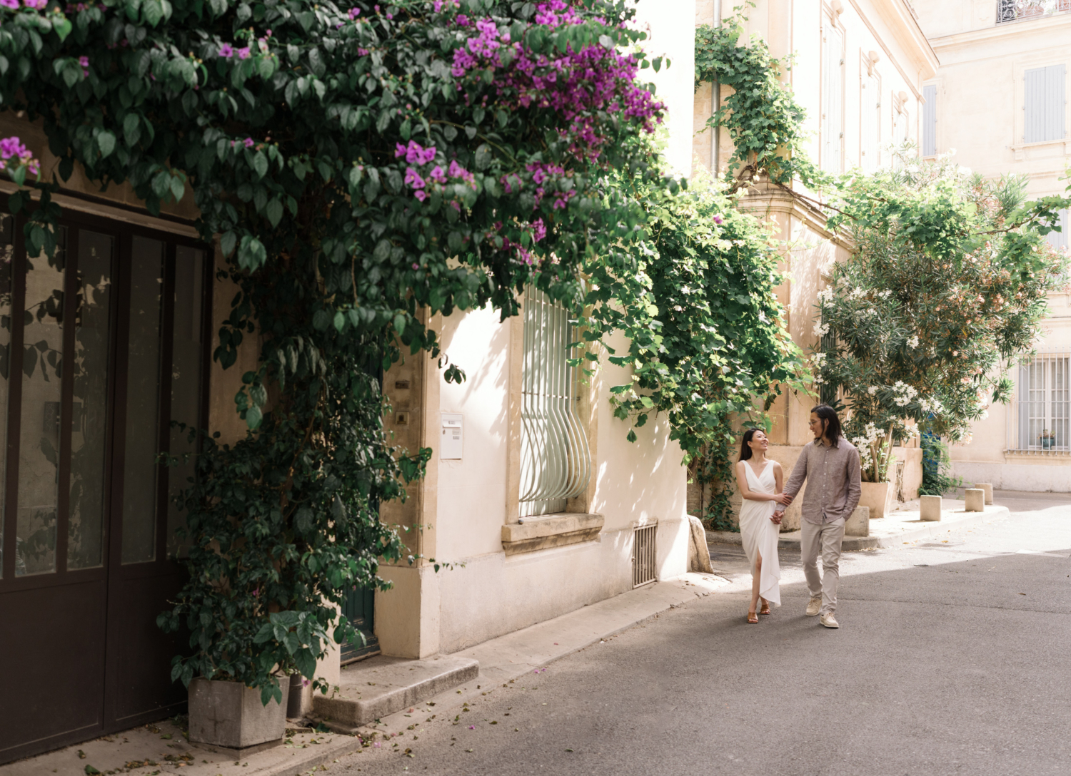 chinese couple laugh and walk down a beautiful street in arles france