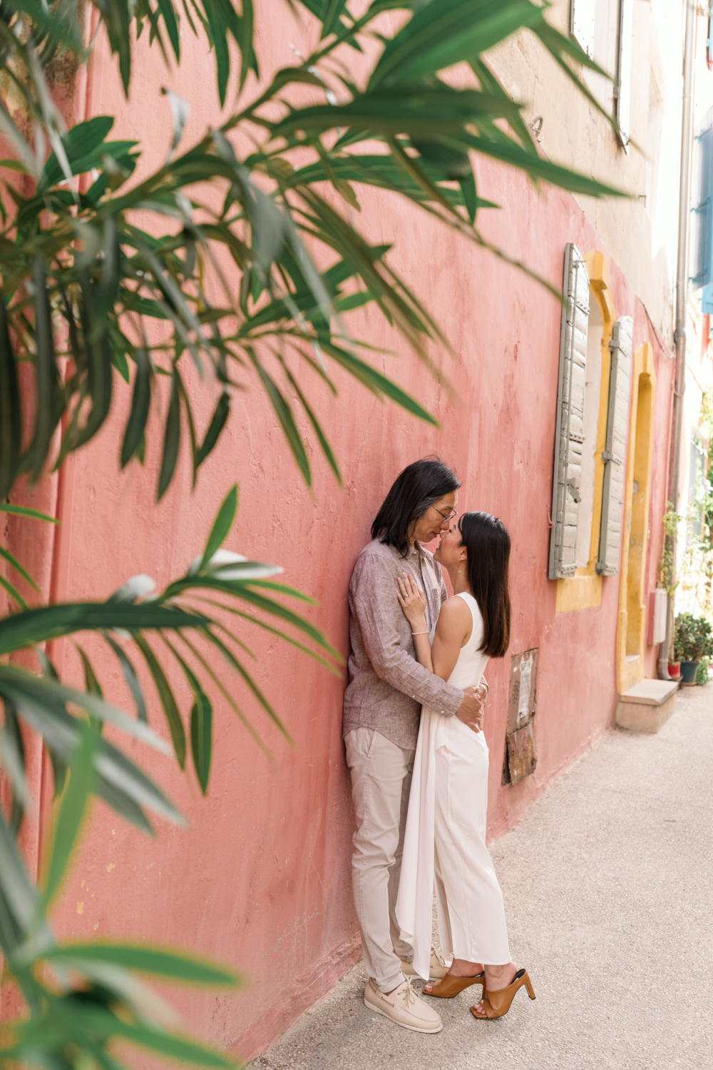 beautiful chinese couple embrace in front of colorful building in arles france