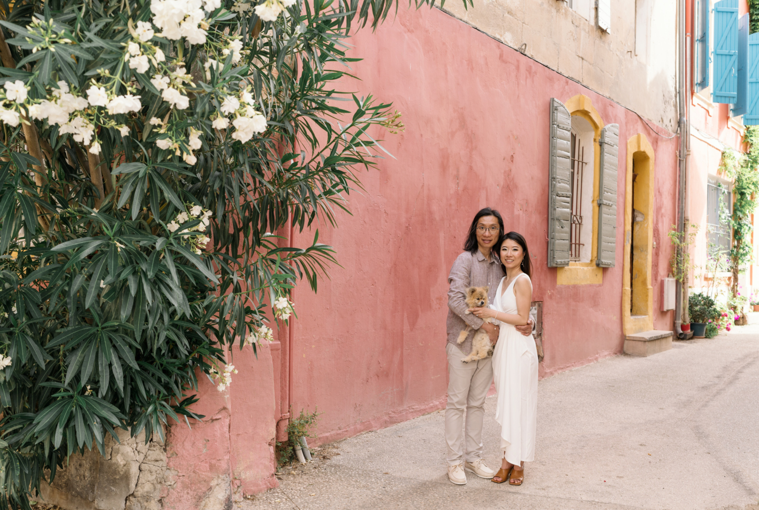 beautiful chinese couple pose with their Pomeranian dog in front of colorful building