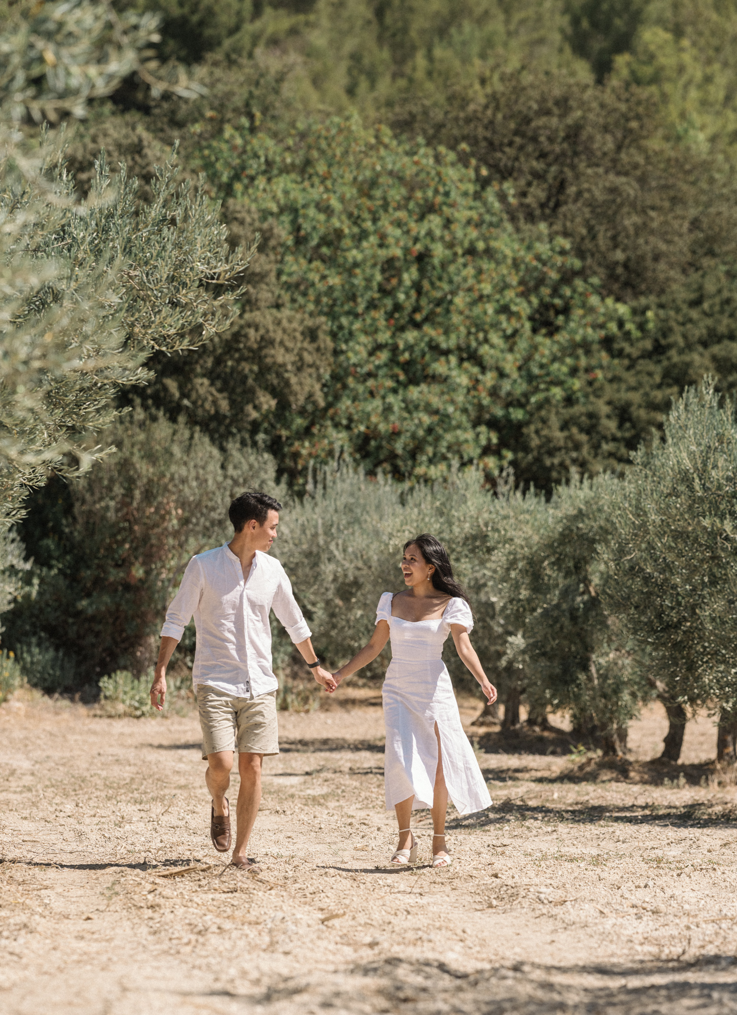couple hold hands and laugh in olive groves les baux de provence