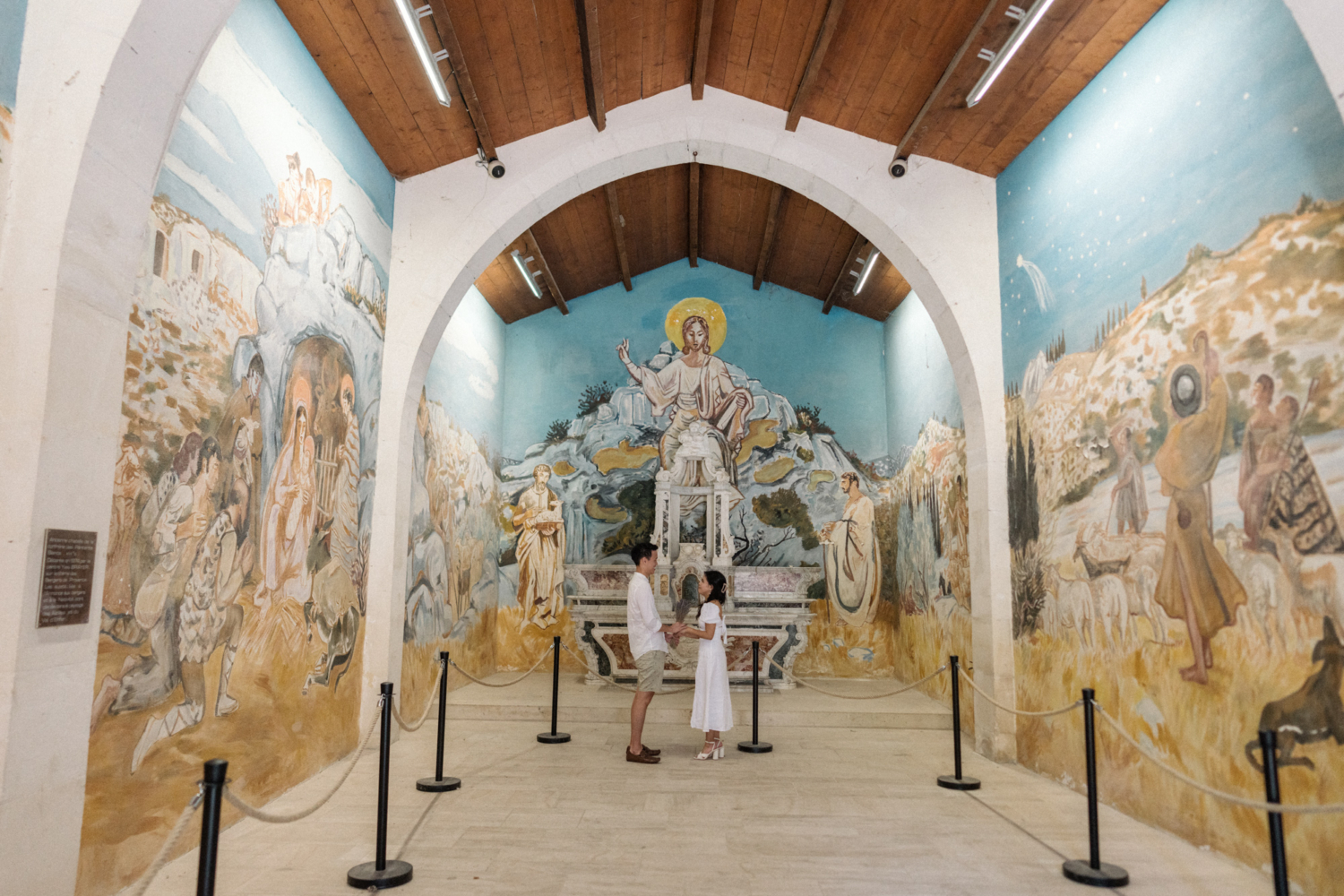 couple hold hands in colorful chapel in les baux de provence