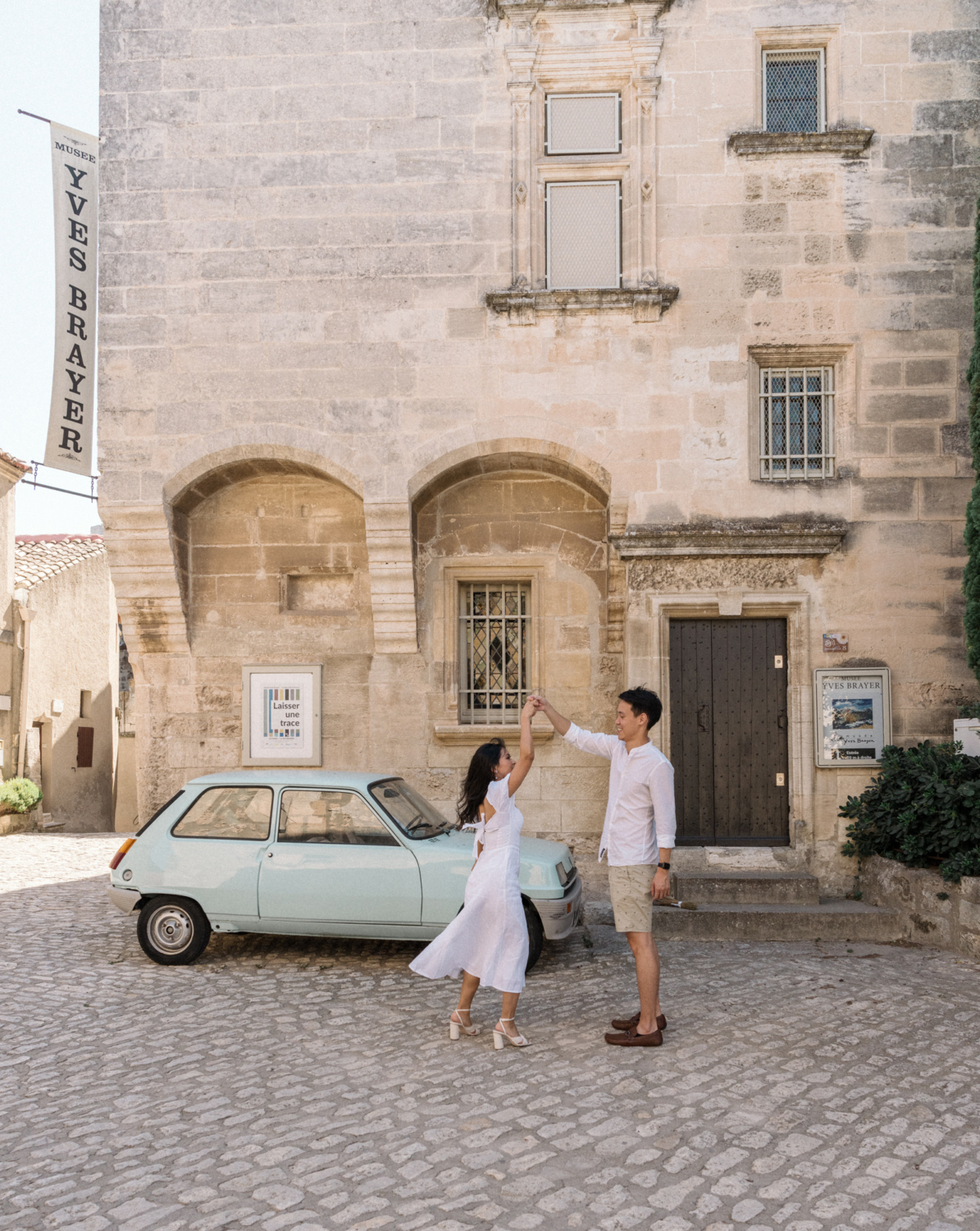 man and woman dance with blue car in background