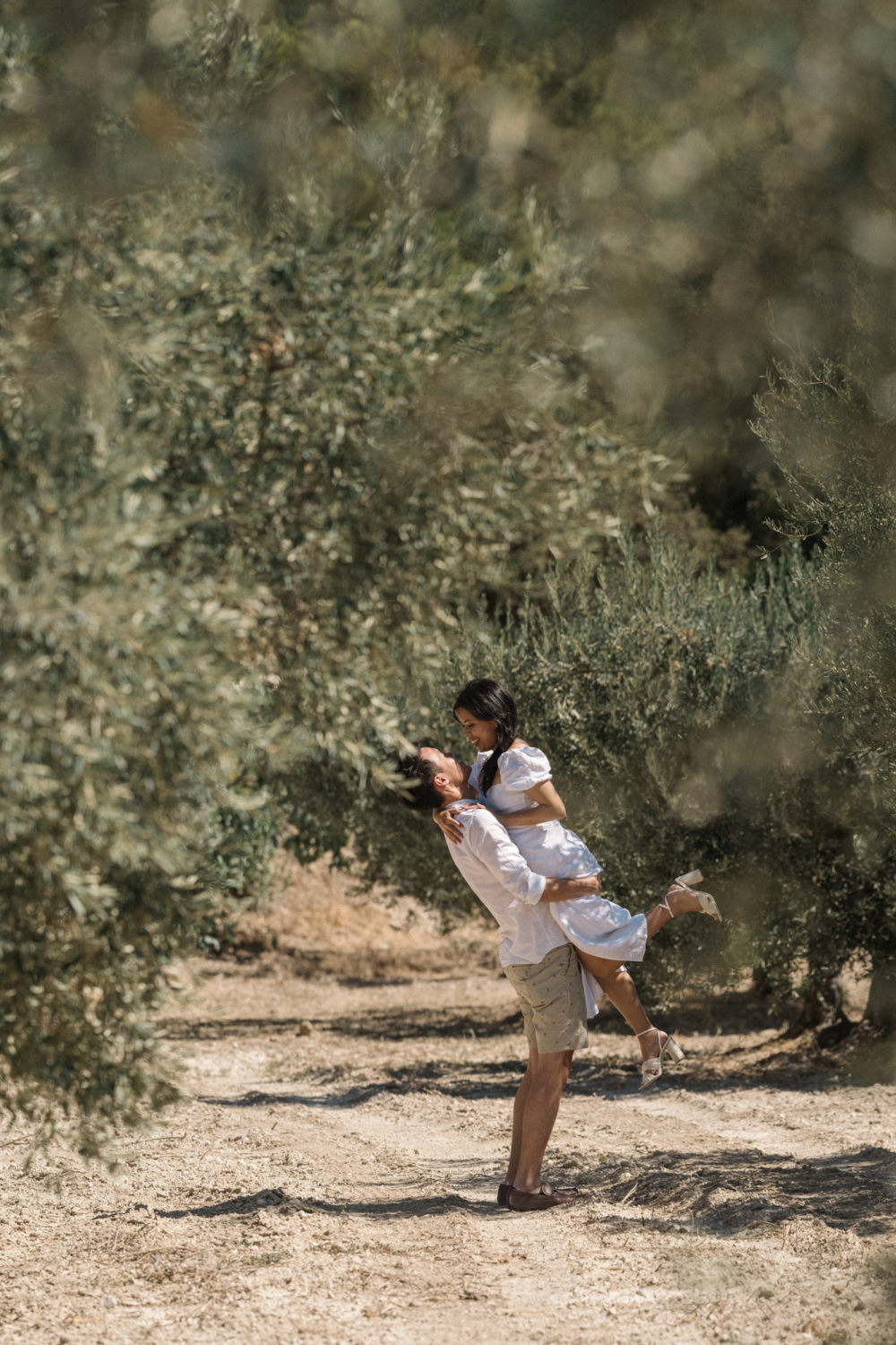 man lifts woman in air in olive grove les baux de provence