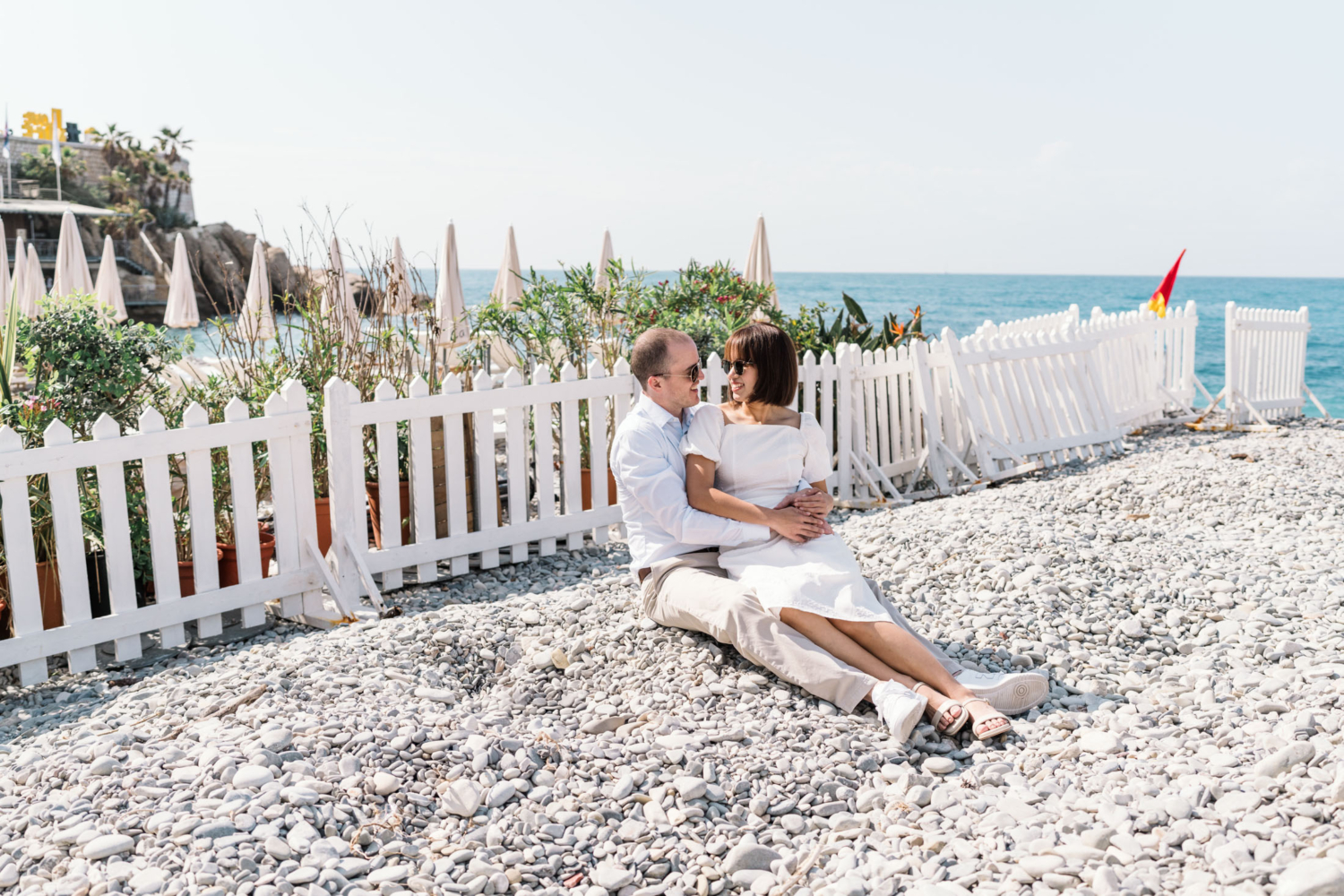 happy couple sit together on beach with view of sea in nice france