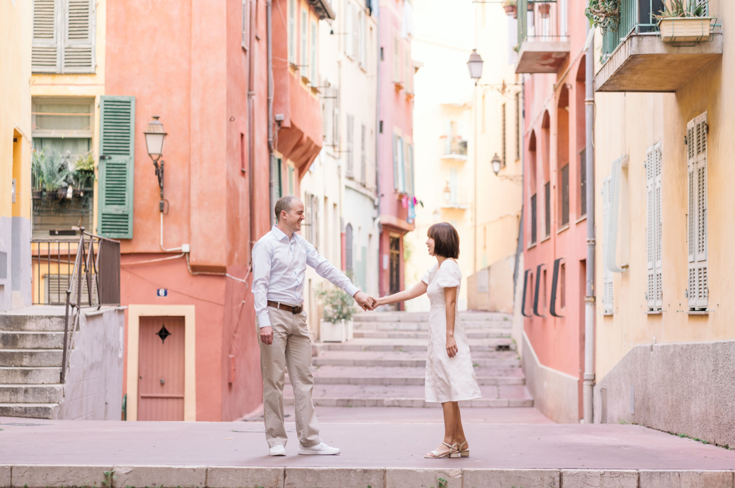 man and woman hold hands as they pose in beautiful colorful neighborhood