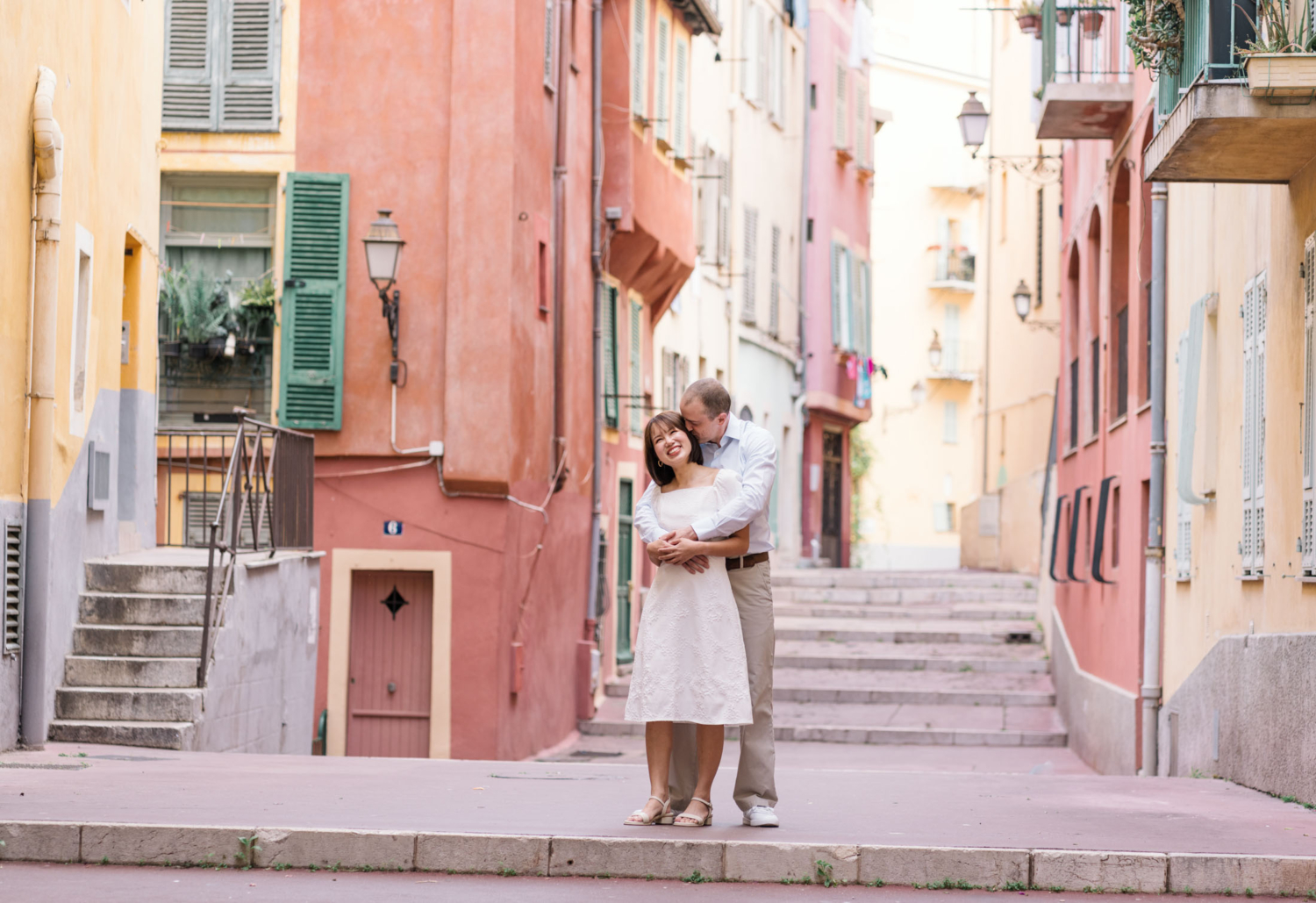 man kisses woman's face as she smiles surrounded by colorful buildings