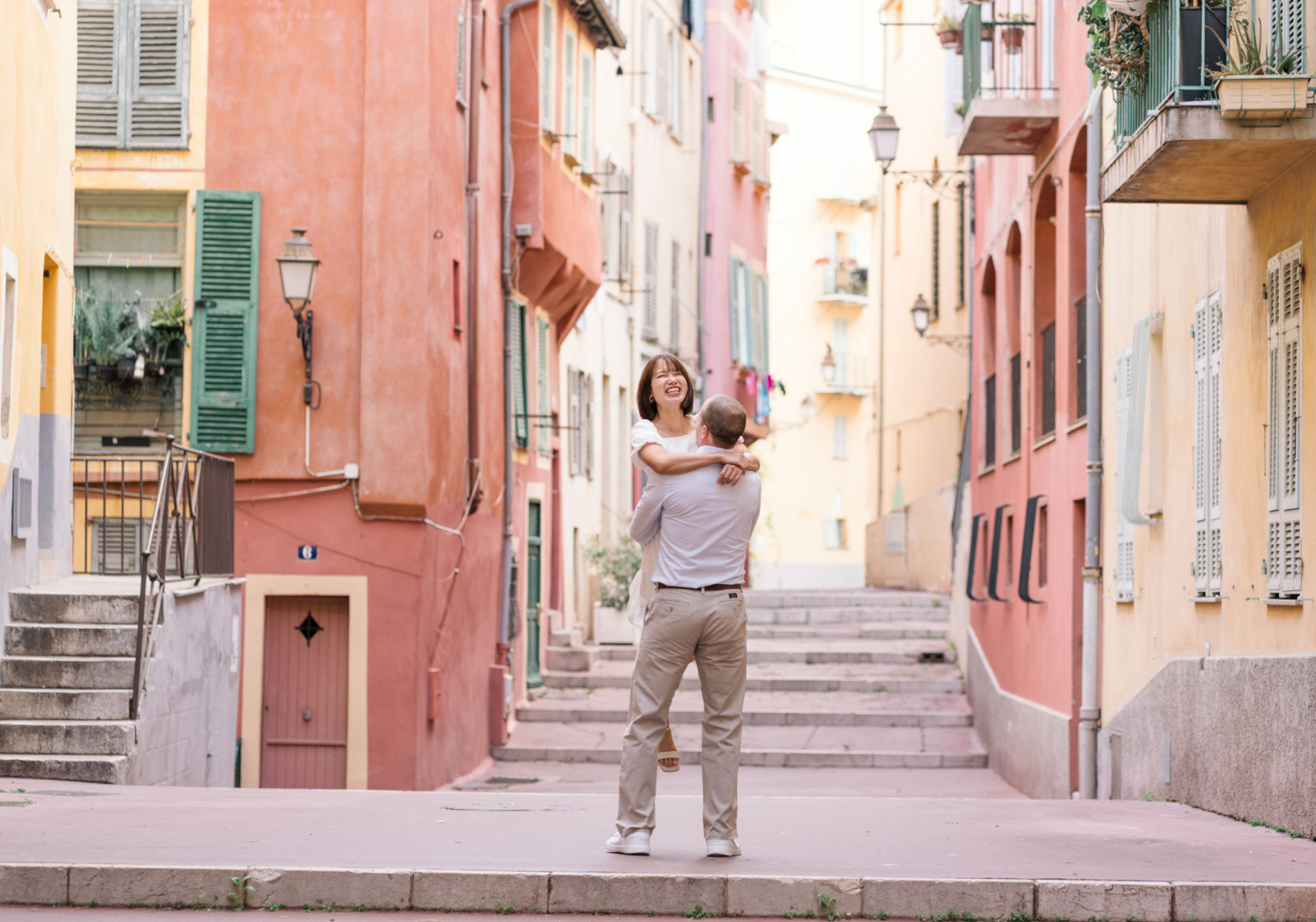 man twirls woman in a circle as she laughs with colorful buildings in background