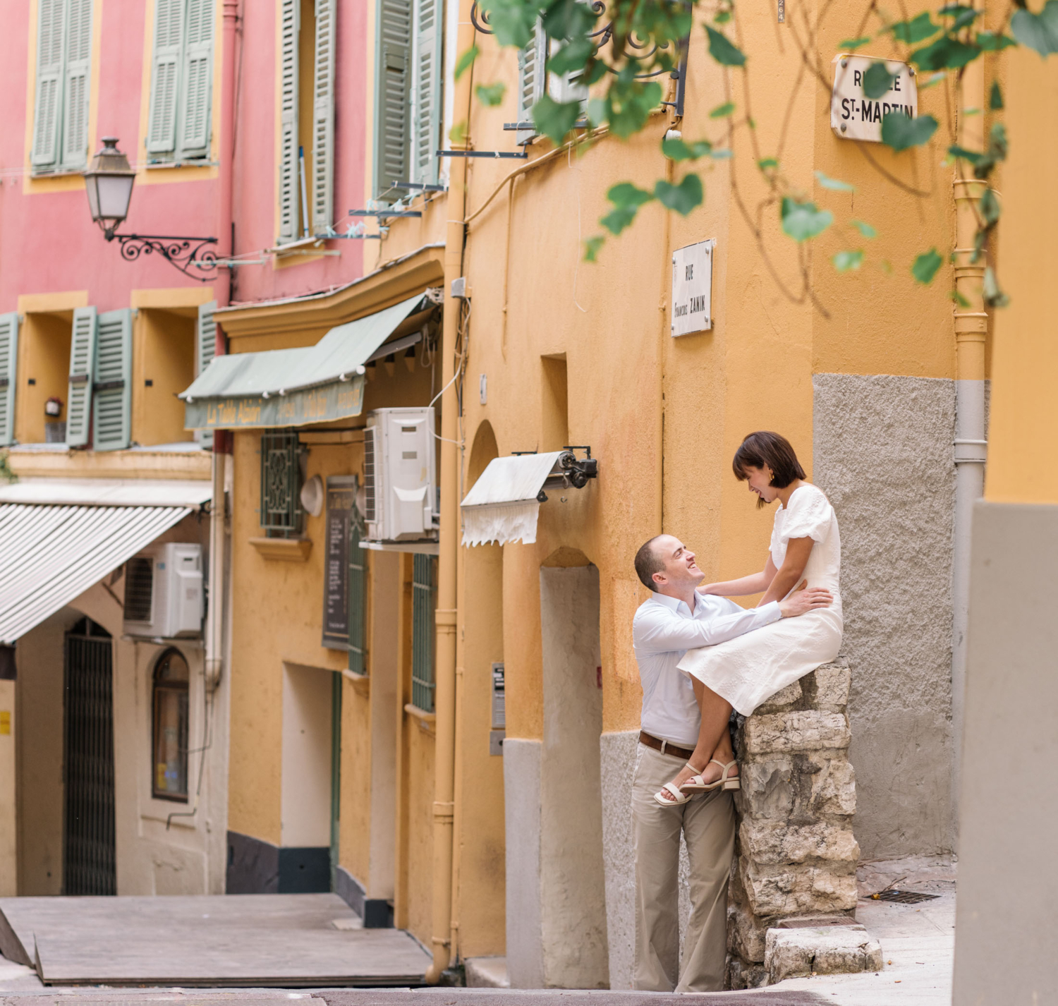 woman sitting on ledge next to man with colorful buildings in background