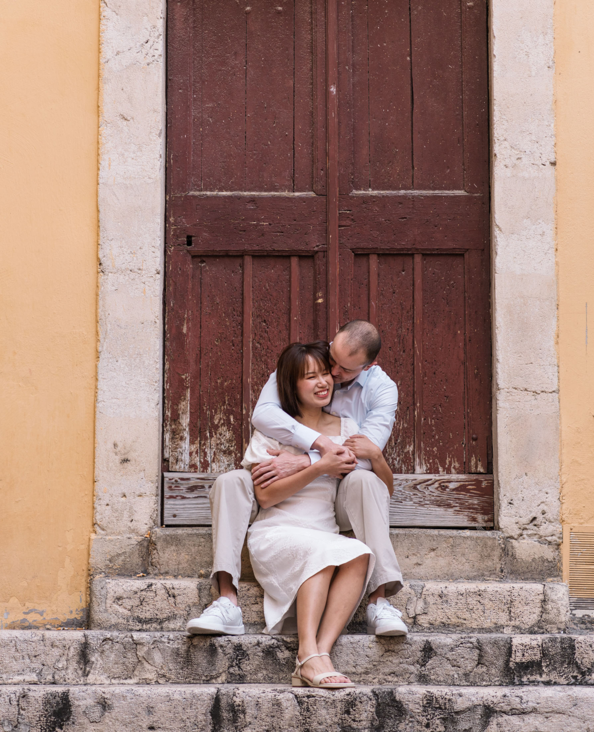 cute couple sitting on a staircase with brown door behind them