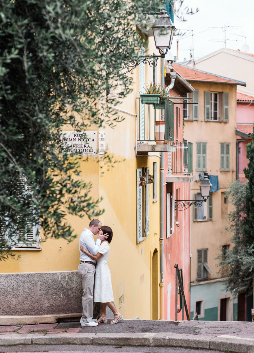 romantic couple kissing with colorful buildings in background in nice france